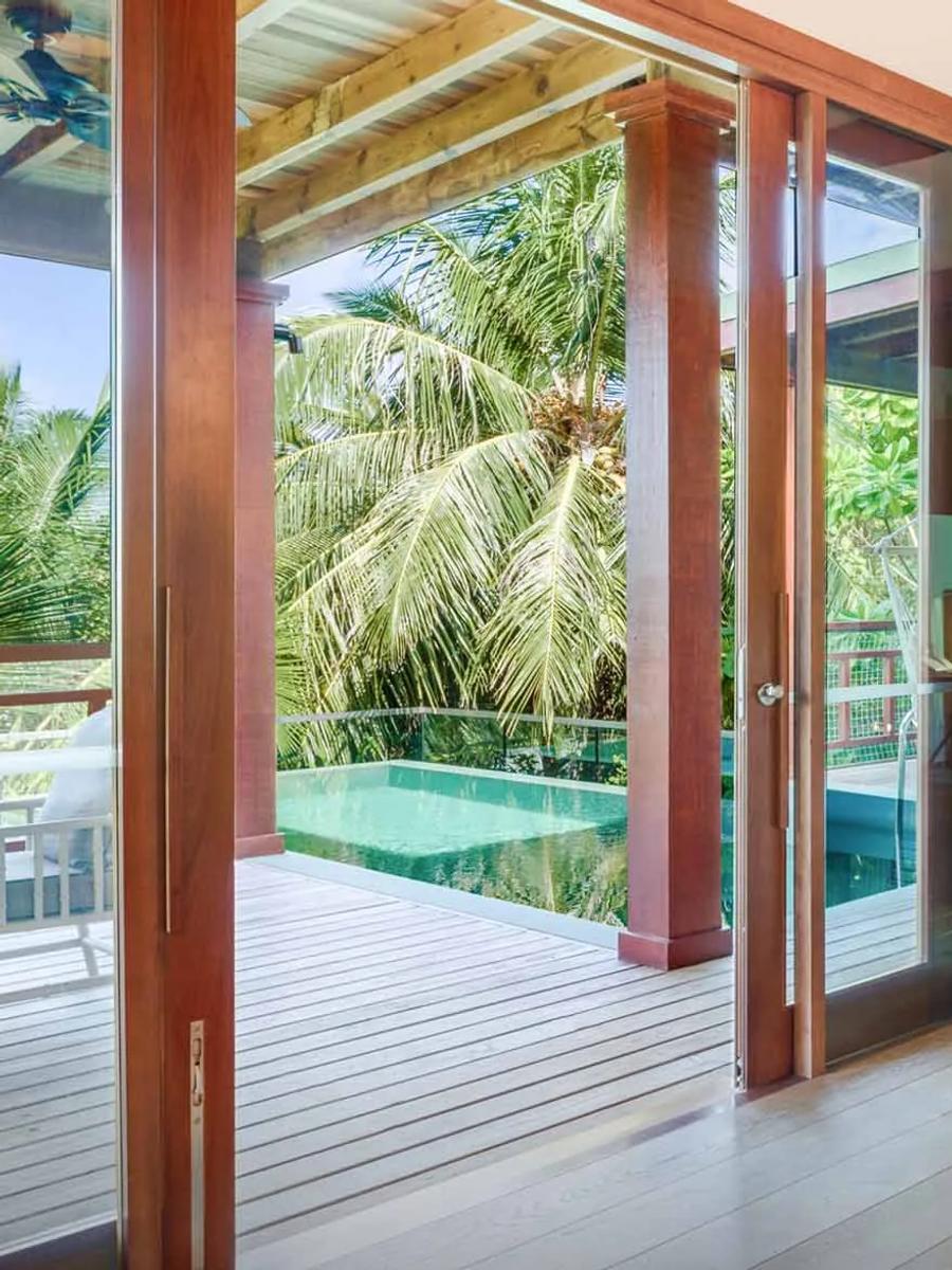 The living area of a Two-Bedroom Treetop Pool Villa at Amilla, opening onto its private pool set among the palms