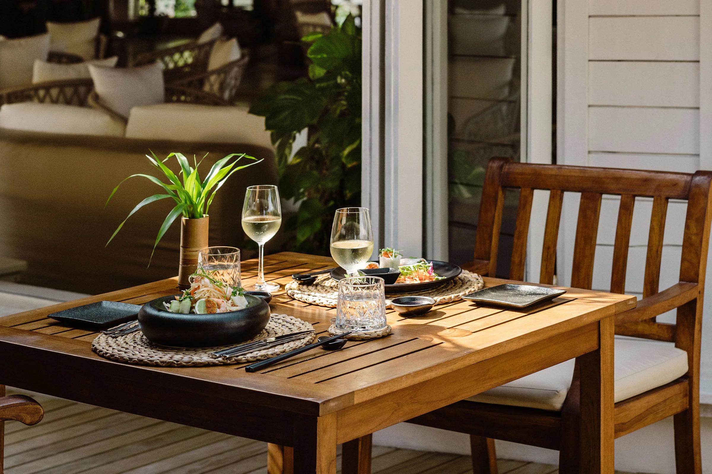 An intimate two-person table set with white wine and small plates on a quiet deck, representative of Iru Fushi's private dining settings — dedicated Cellar photography to follow
