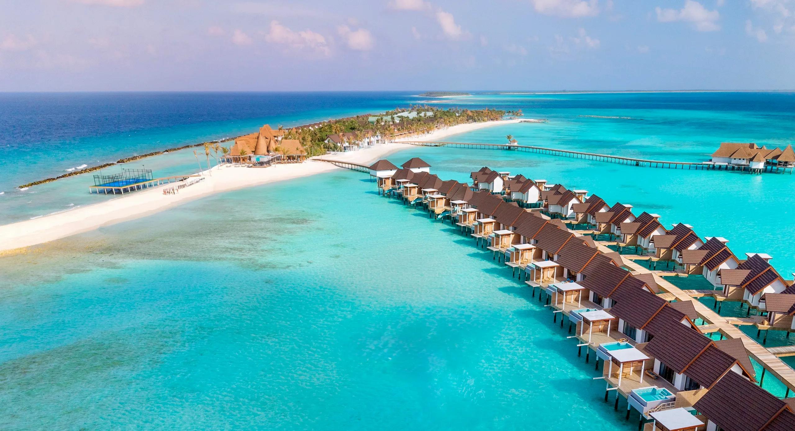 An aerial view of Meyyafushi's beach, pools and villa rooftops set against the surrounding reef