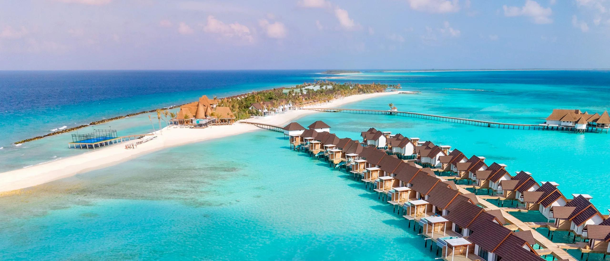 An aerial view of Meyyafushi's beach, pools and villa rooftops set against the surrounding reef