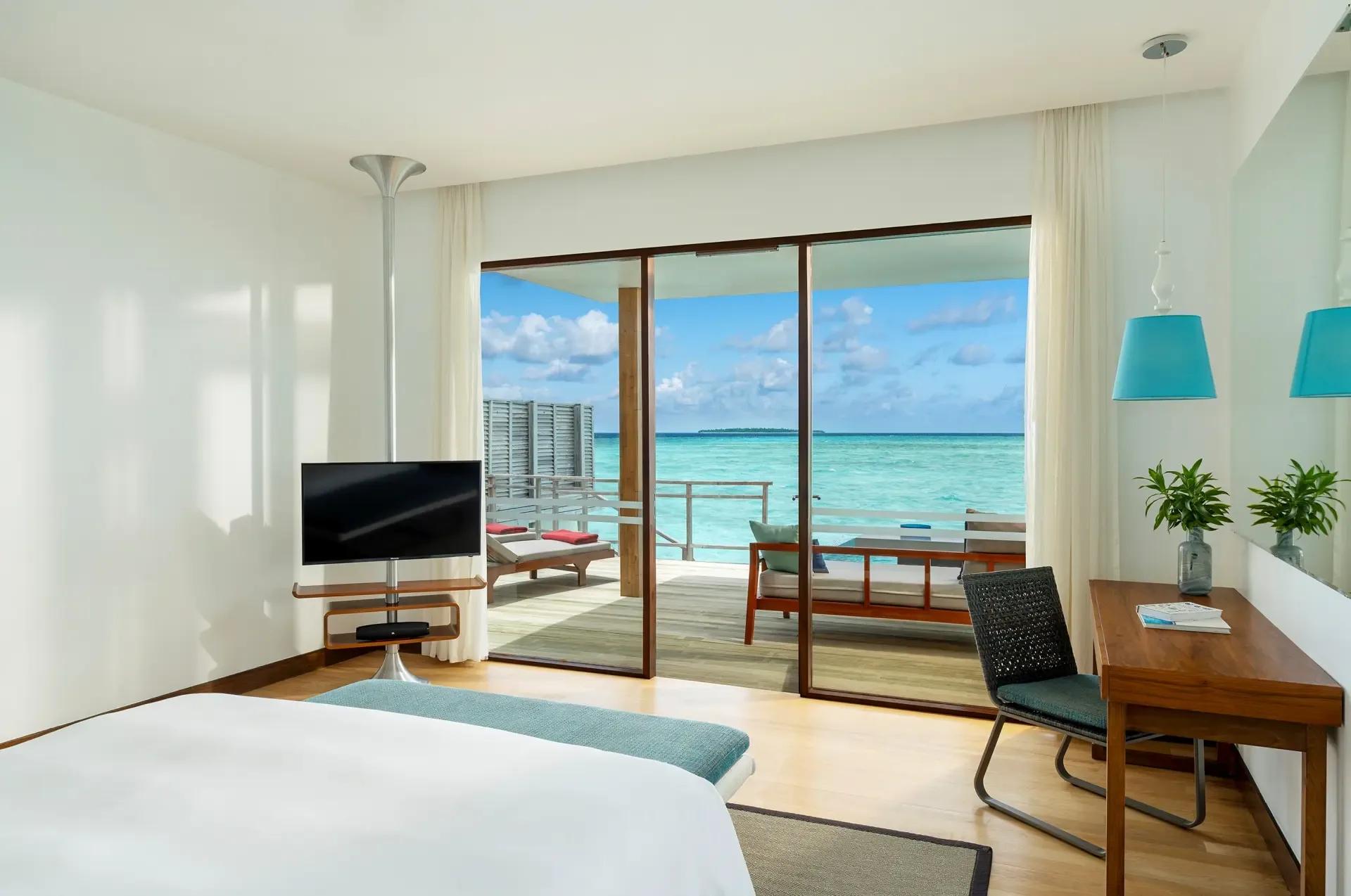 Interior of a Lagoon Villa with Pool, king bed facing floor-to-ceiling windows onto the open lagoon