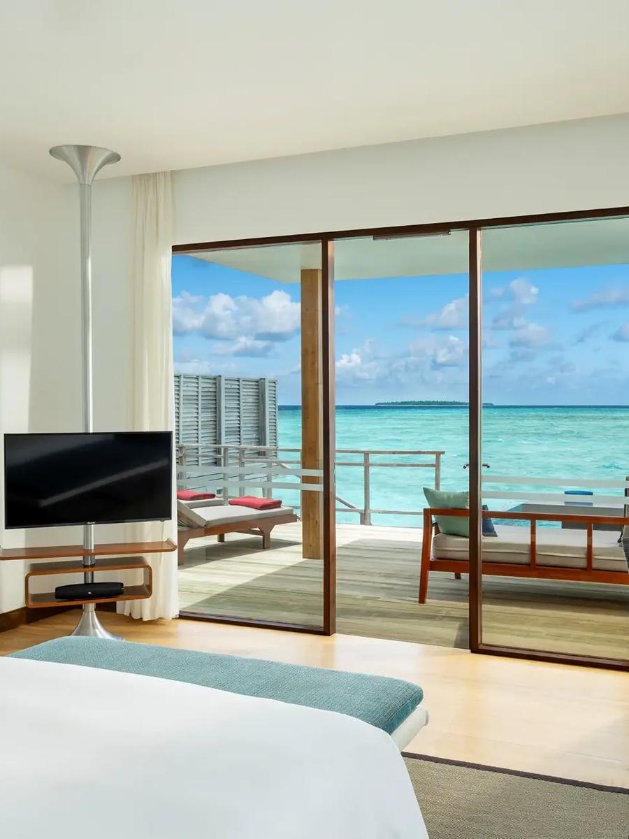 Interior of a Lagoon Villa with Pool, king bed facing floor-to-ceiling windows onto the open lagoon