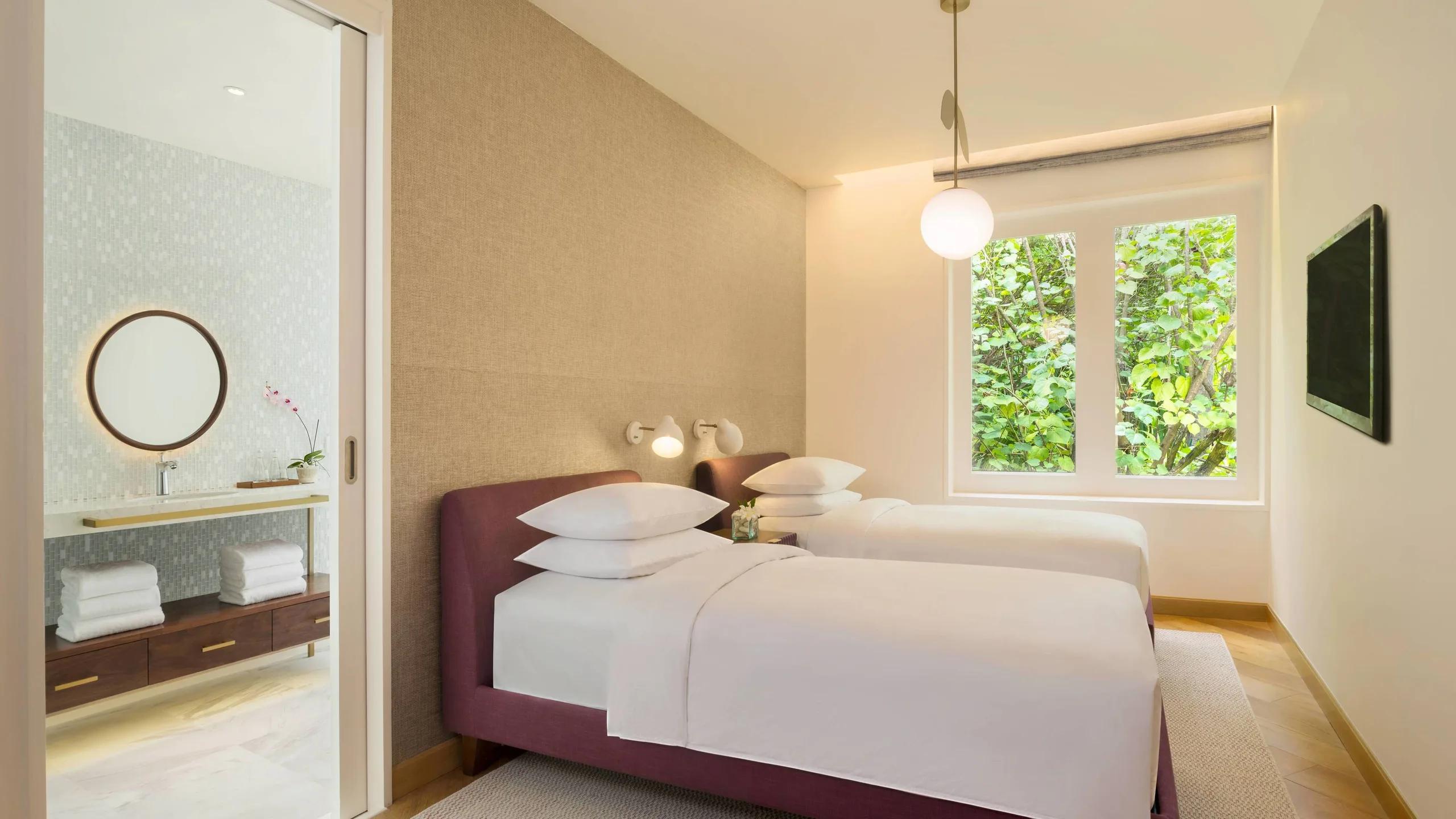 The twin room in a Duplex Beach Pool Villa, two beds with an en-suite bathroom visible through the sliding door