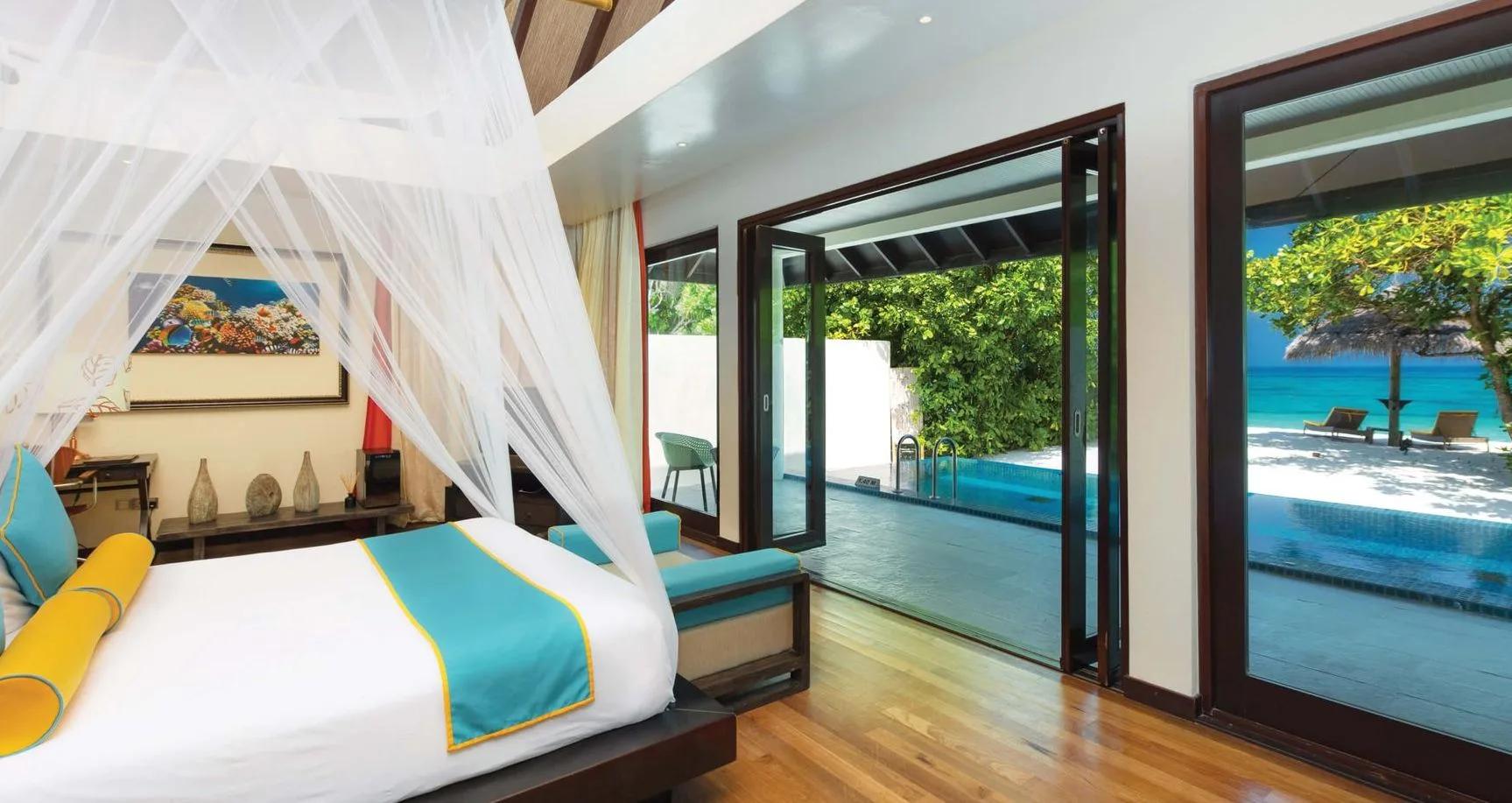 A Sunset Beach Villa with Pool's bedroom, sliding doors open to its private pool and the beach beyond