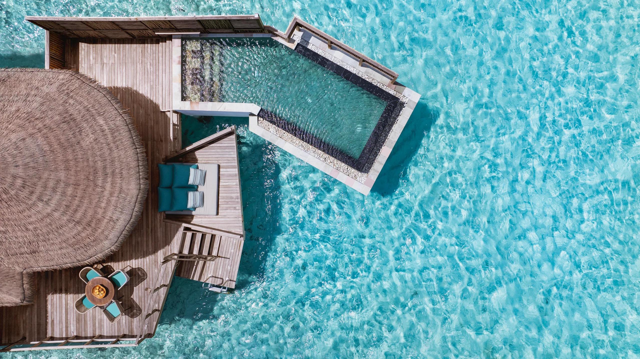 Overhead view of a Water Villa's private plunge pool and sun deck extending over the turquoise lagoon.