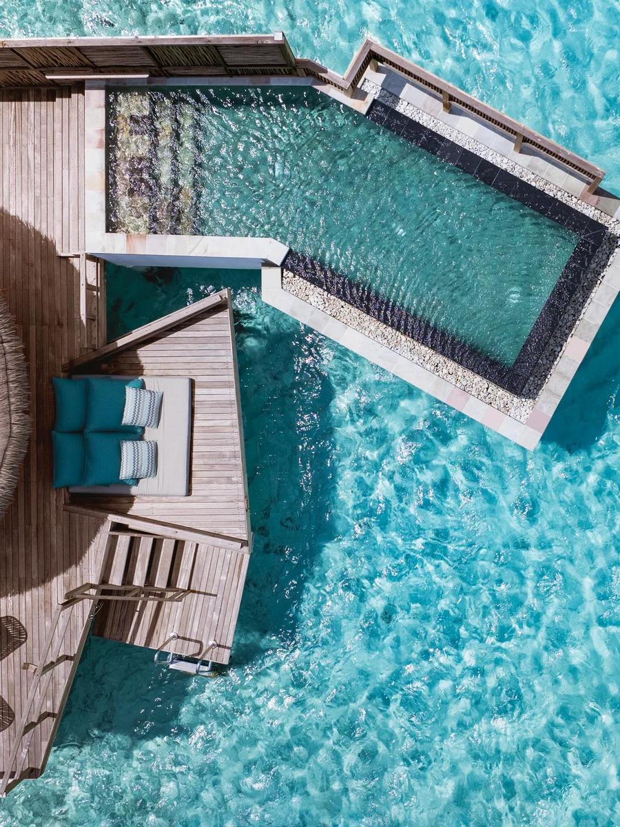Overhead view of a Water Villa's private plunge pool and sun deck extending over the turquoise lagoon.