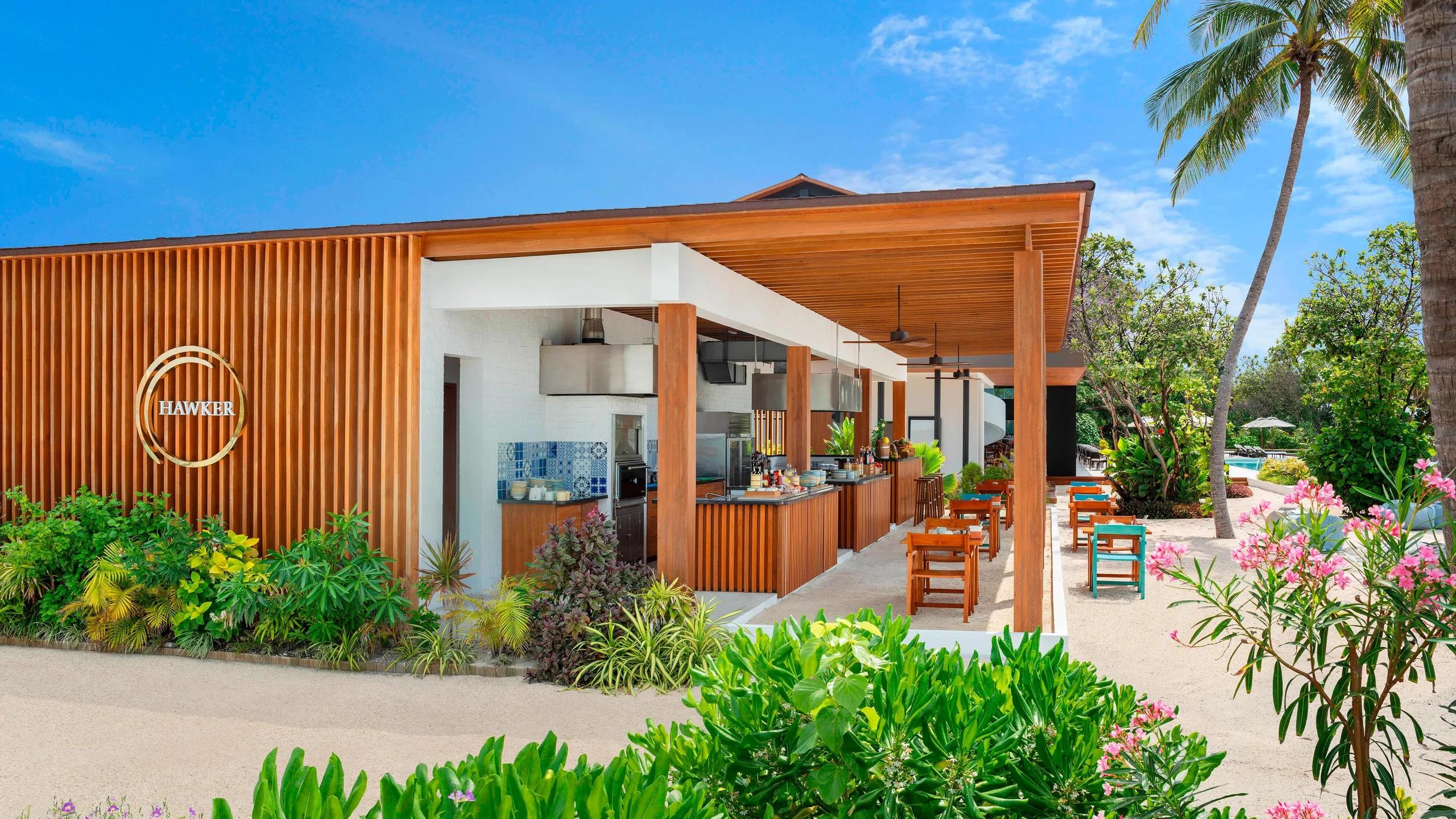 Hawker's timber-slat entrance and open kitchen counter, palm trees framing the terrace