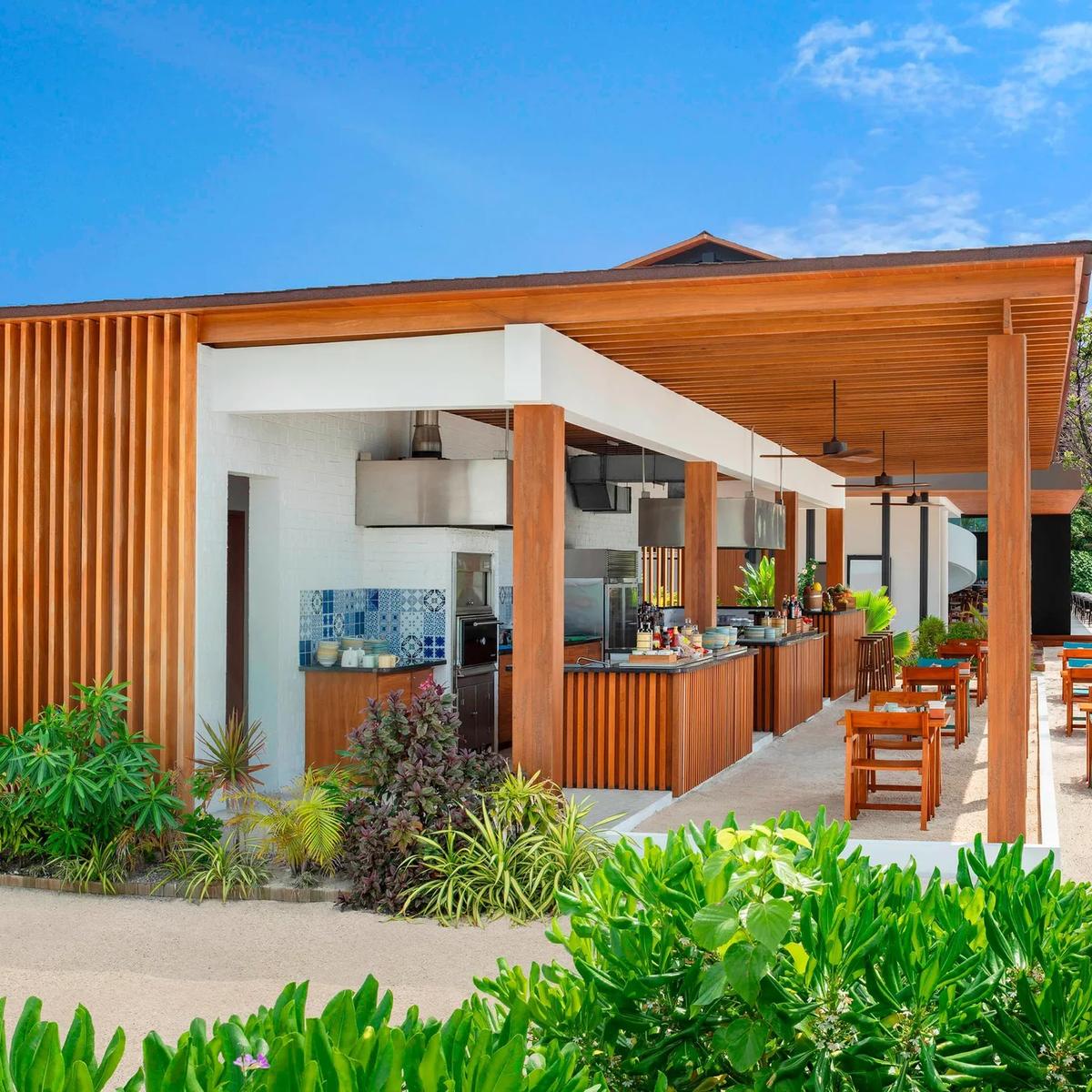 Hawker's timber-slat entrance and open kitchen counter, palm trees framing the terrace