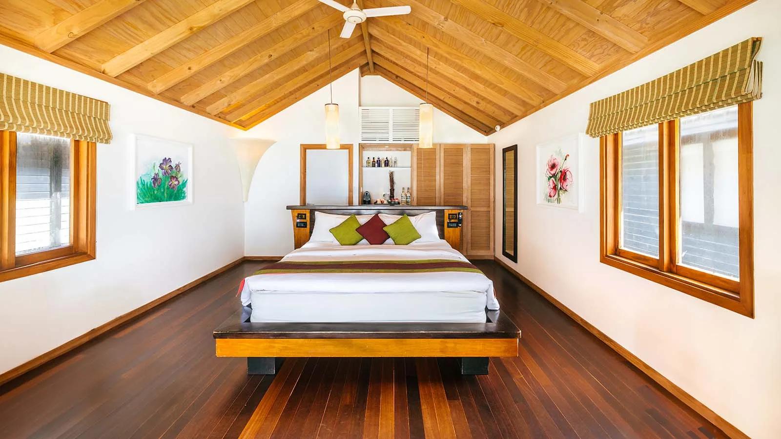 Beach Villa bedroom with dark wood beams and a sliding door onto a private beachfront terrace