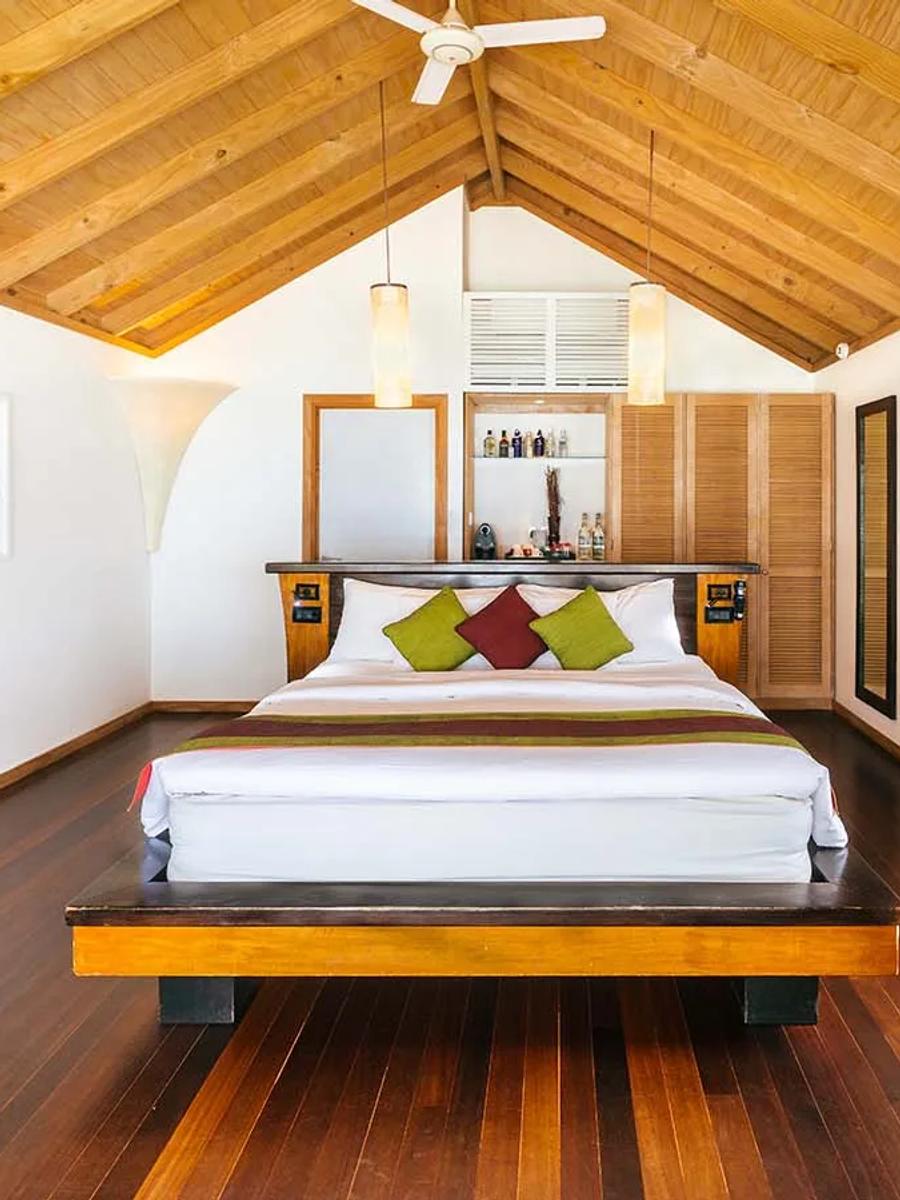 Beach Villa bedroom with dark wood beams and a sliding door onto a private beachfront terrace