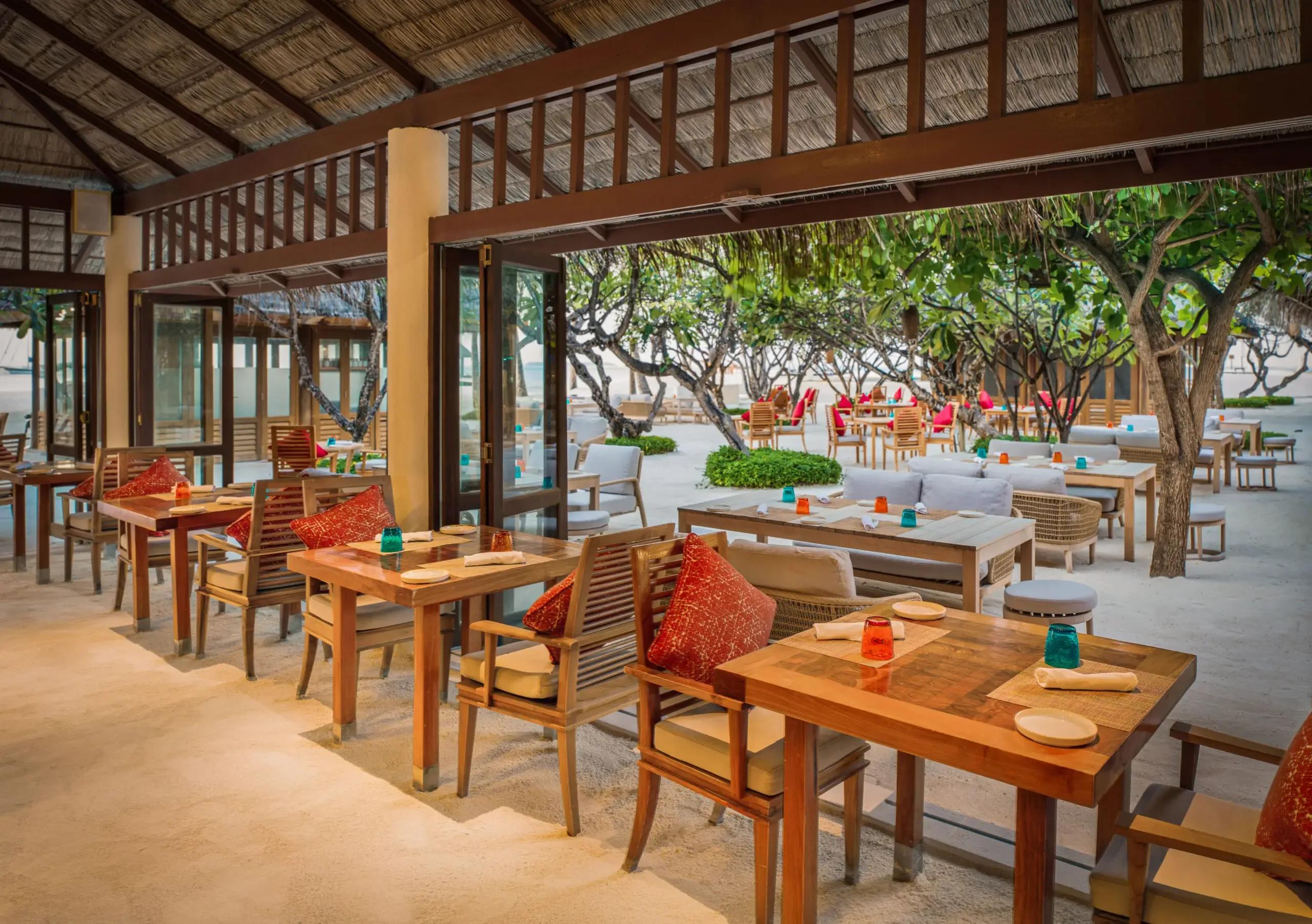 The espresso bar and lounge seating inside Atoll Market's thatched-roof dining hall at Conrad Maldives Rangali