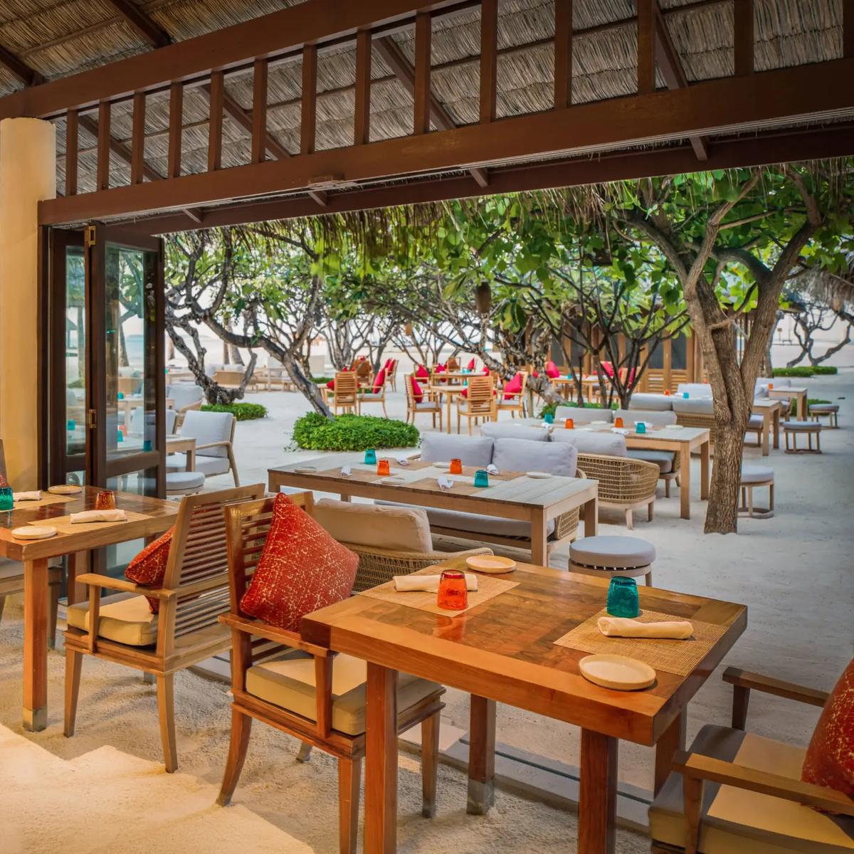 The espresso bar and lounge seating inside Atoll Market's thatched-roof dining hall at Conrad Maldives Rangali