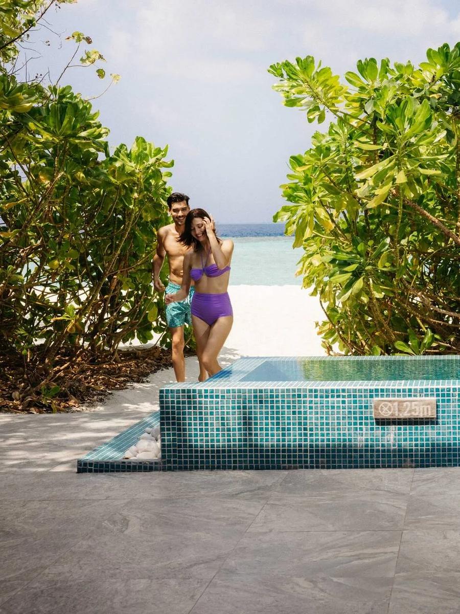 A couple walking from the beach path toward a Lagoon Beach Villa's tiled private plunge pool
