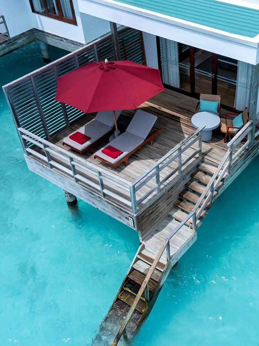 Aerial view of a Water Villa's overwater deck and open-air lounge chairs above the turquoise lagoon