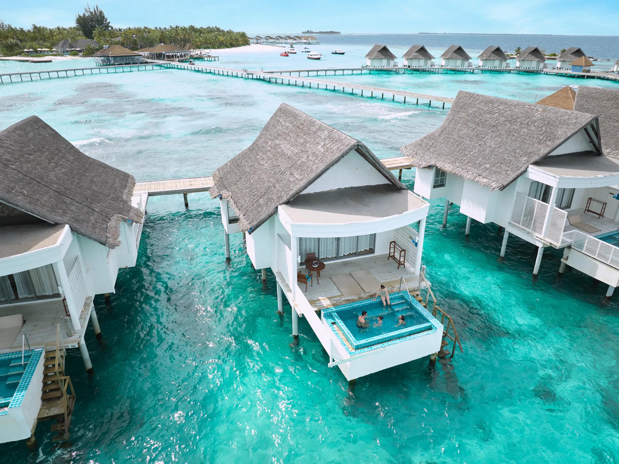 Guests swimming in a private overwater pool with the lagoon and jetties stretching behind