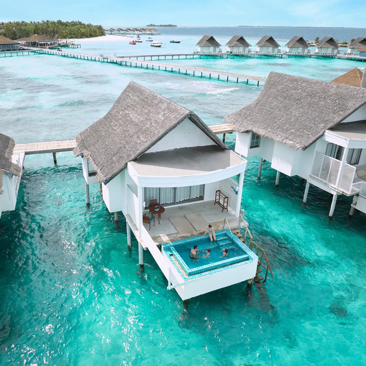 Guests swimming in the private pool of a Club Sunset Overwater Pool Villa, the tier of villa The Club serves
