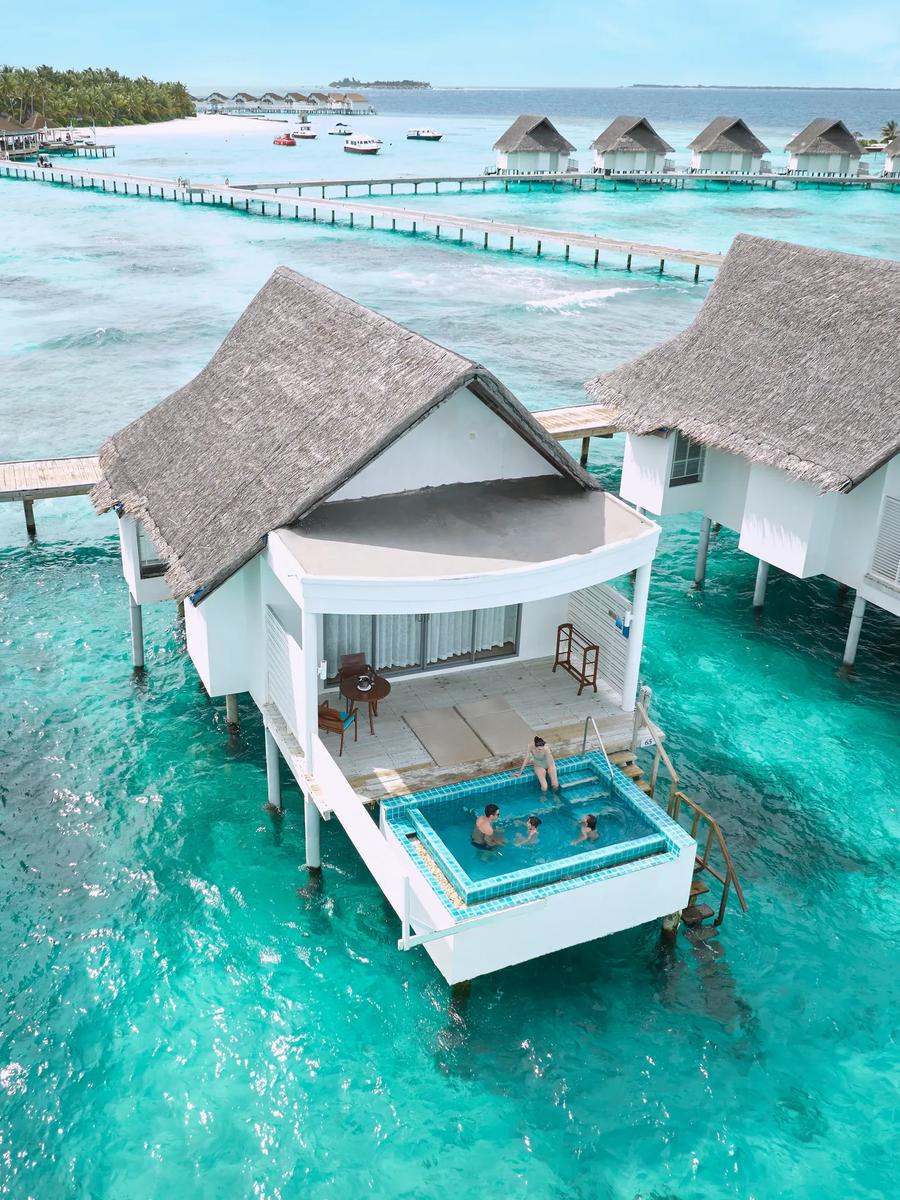 Guests swimming in a private overwater pool with the lagoon and jetties stretching behind