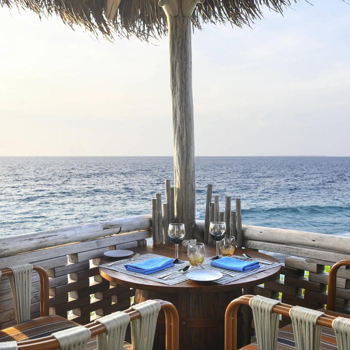 A table set for two at Kaashi, under a thatched roof looking straight out over open water
