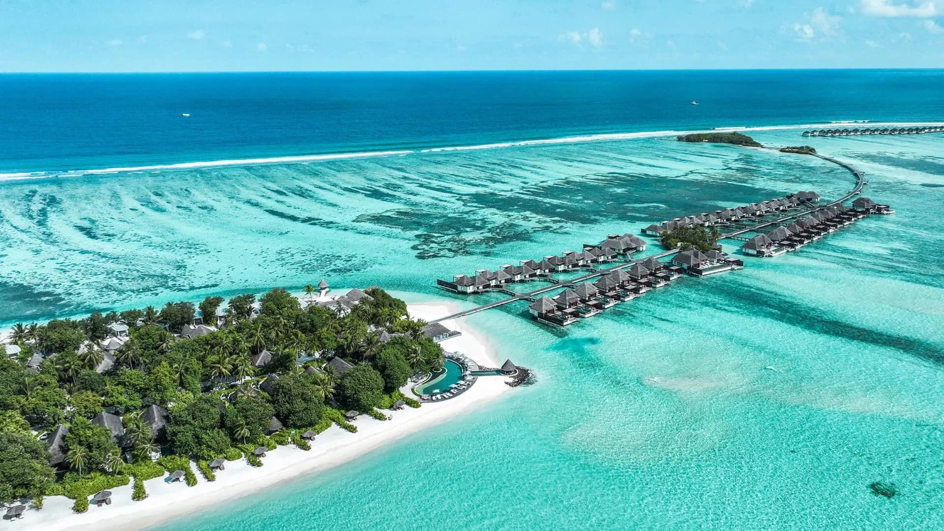 Aerial view of Four Seasons Resort Maldives at Kuda Huraa, its overwater villas running out along the reef edge in North Malé Atoll