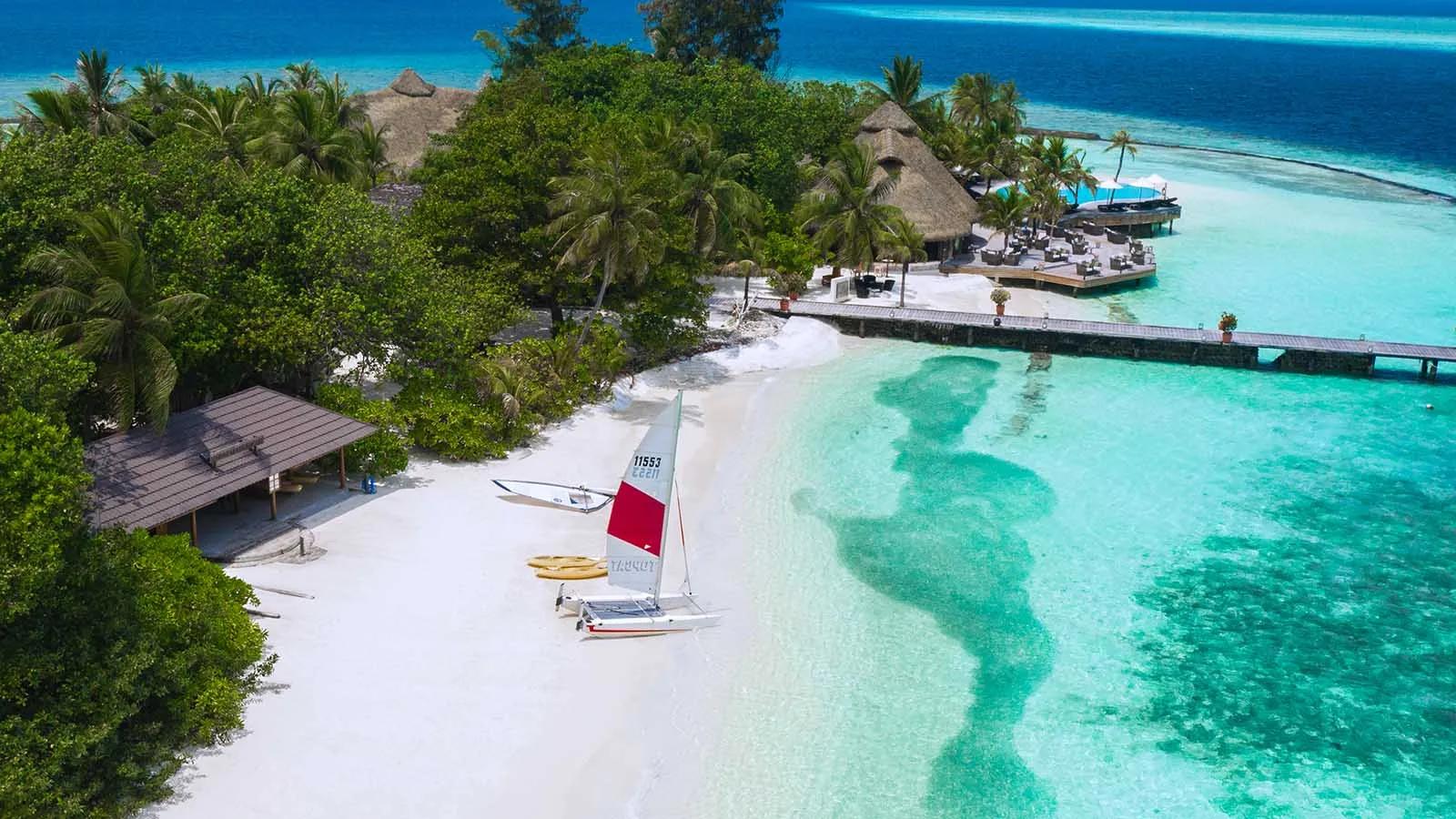 The watersports hut and beach, with a catamaran and kayaks laid out ready to launch and the pool deck beyond