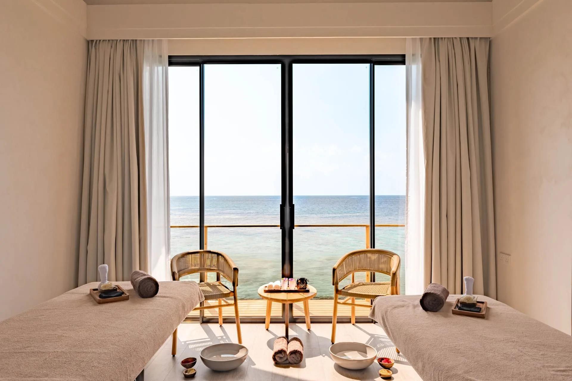 A couples treatment suite at Kandu Spa, floor-to-ceiling glass facing the reef