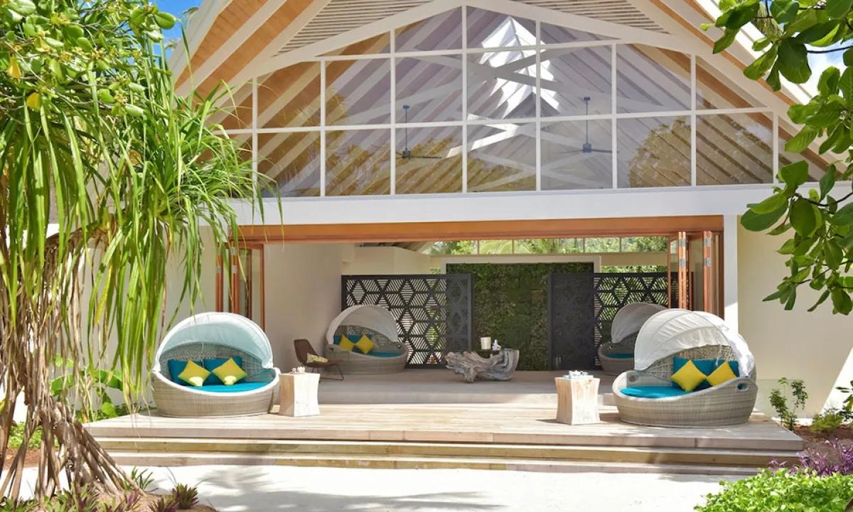 Canopied daybeds on a wooden deck outside esKape Spa's treatment pavilion