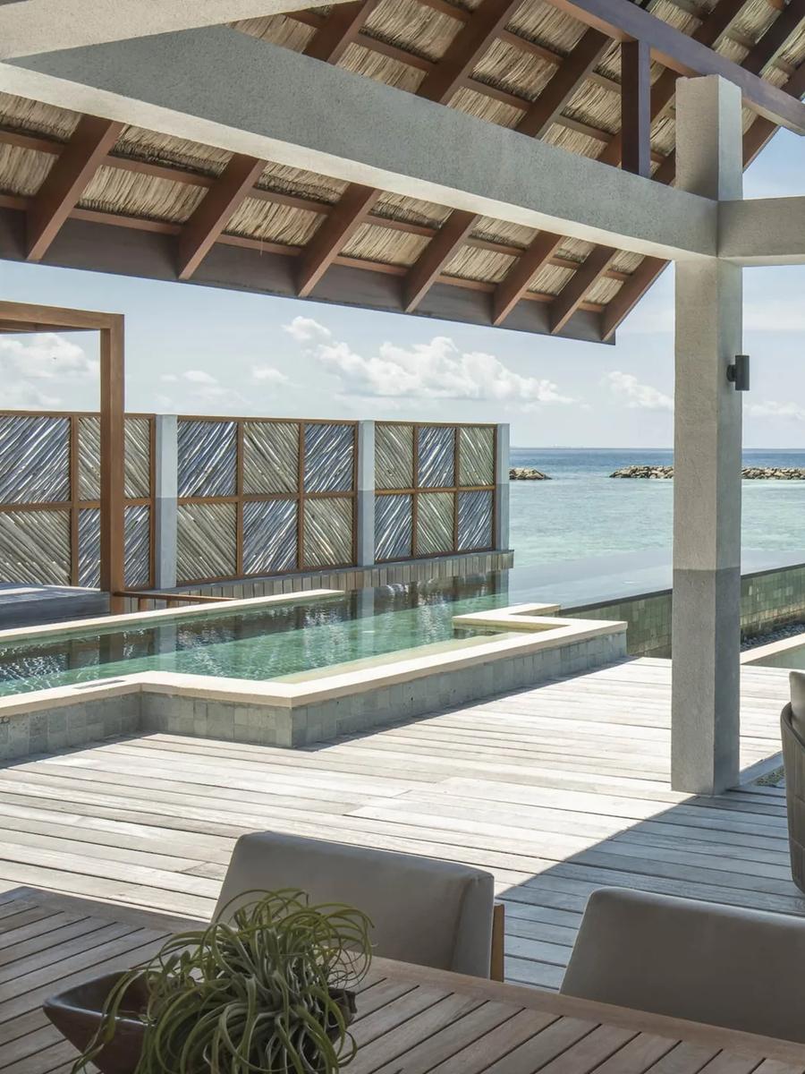 The overwater deck and plunge pool of a Sunrise Family Water Villa, loungers set out with the reef breakwater visible beyond