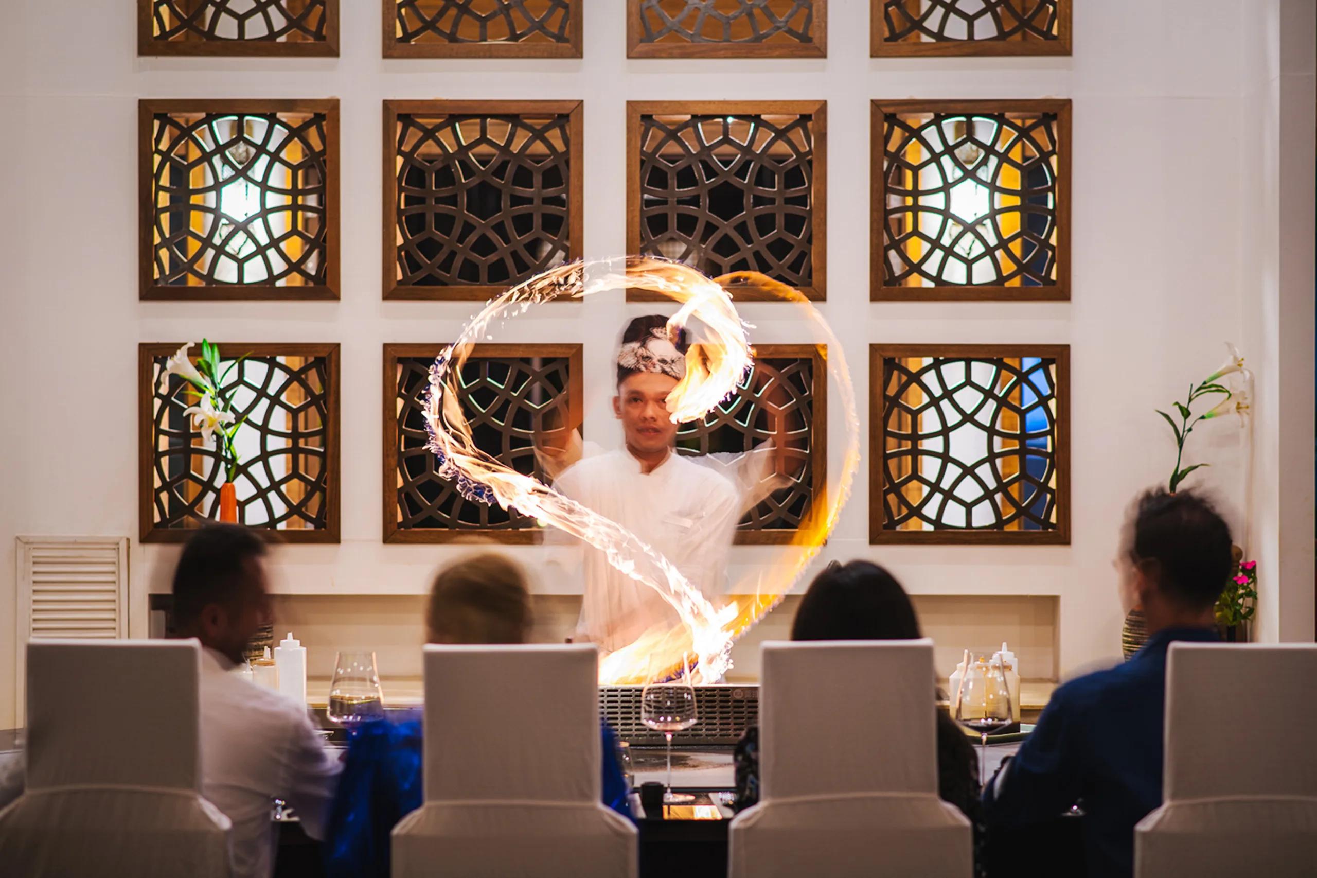 A chef performing a teppanyaki fire show at Samsara Asian Fusion, Hideaway Beach Resort & Spa