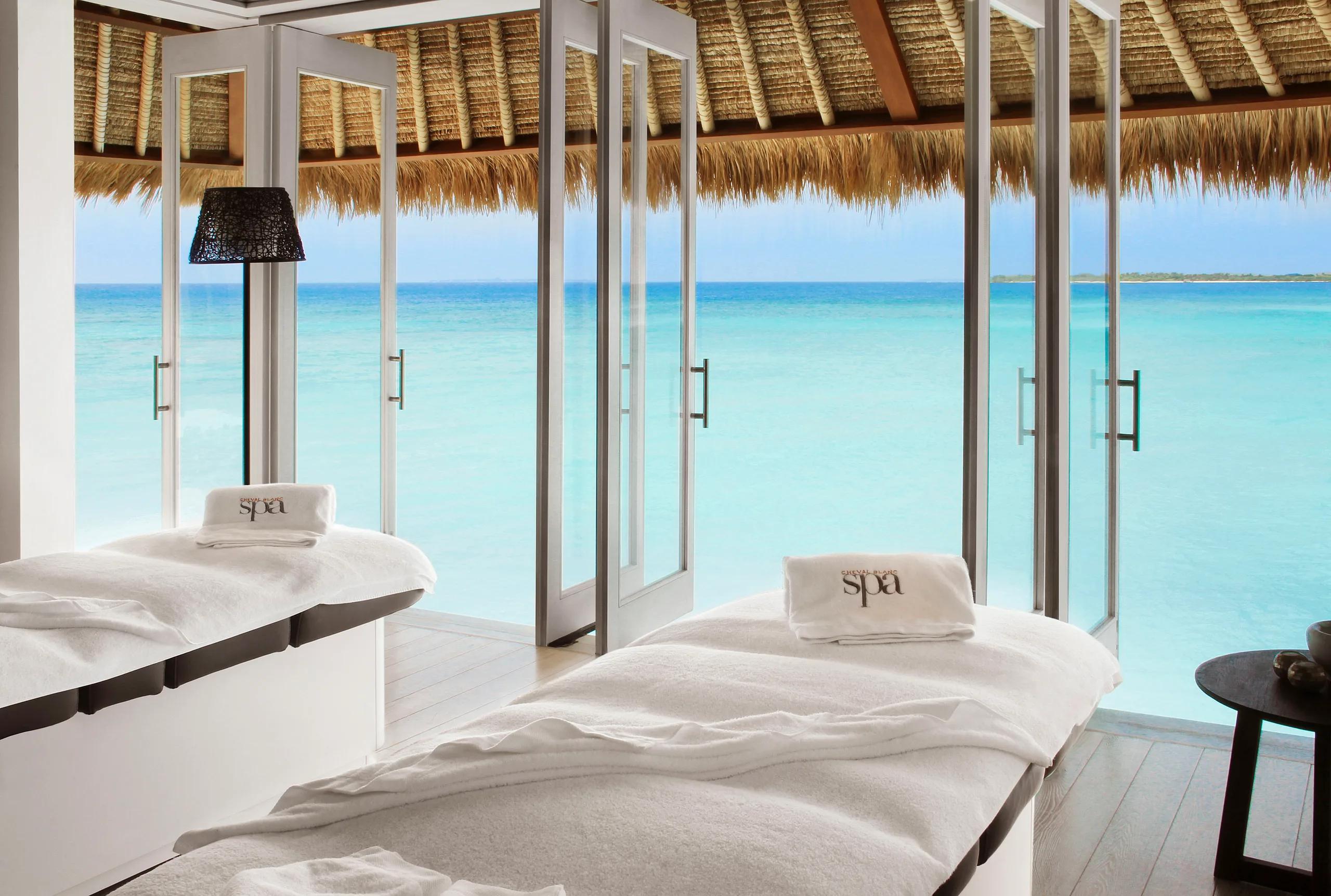 Two spa treatment beds facing floor-to-ceiling doors open to the turquoise lagoon at Spa Cheval Blanc Island