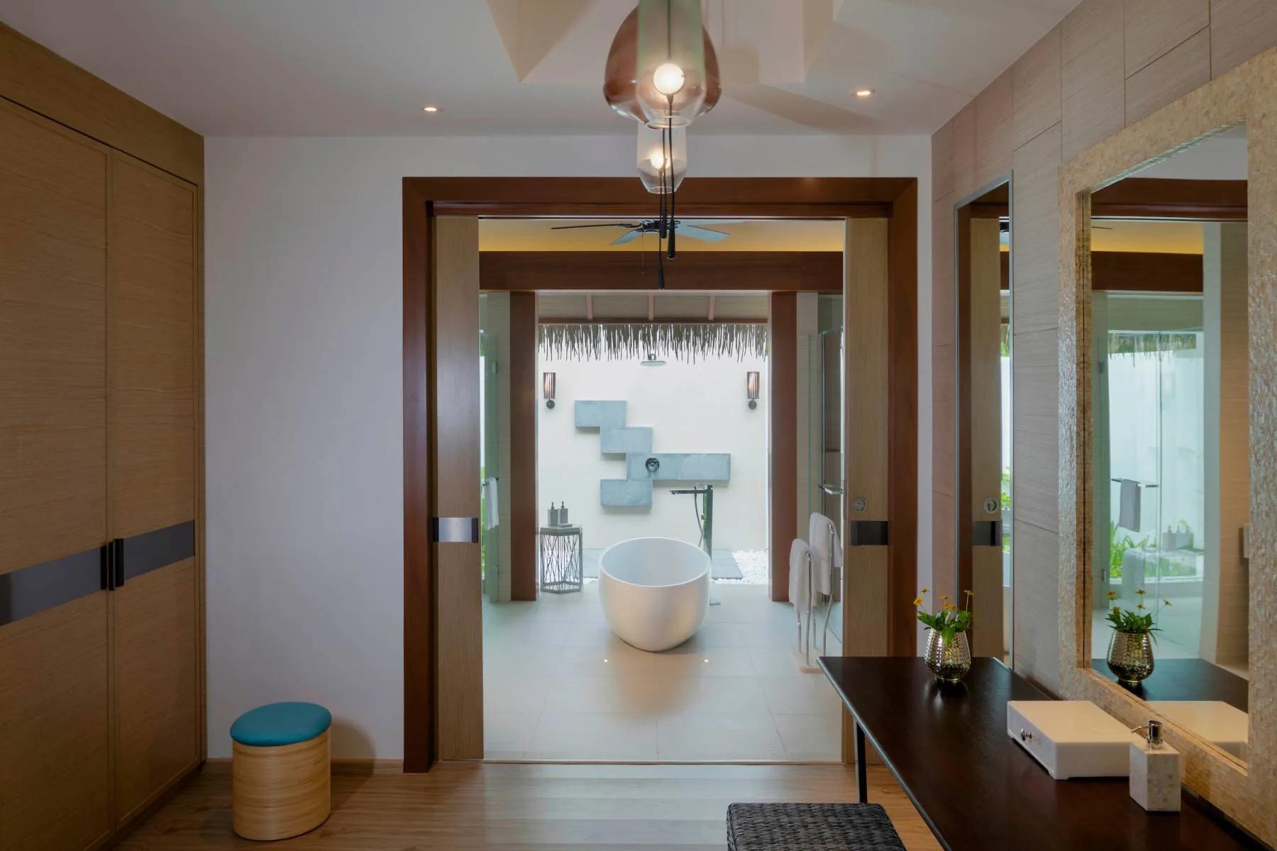 An indoor-outdoor bathroom with an island tub inside a Beach Villa