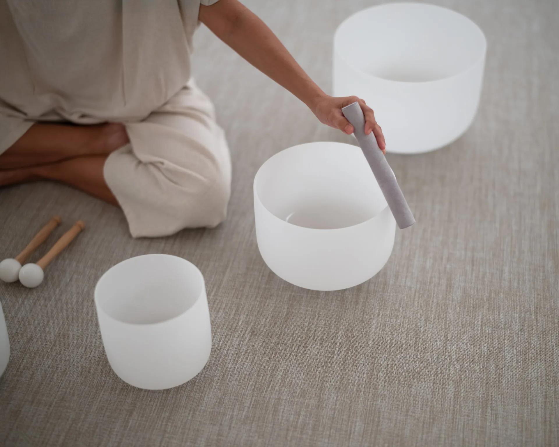 Crystal singing bowls and mallets arranged on a treatment-room floor at Devarana Wellness, Dusit Thani Maldives