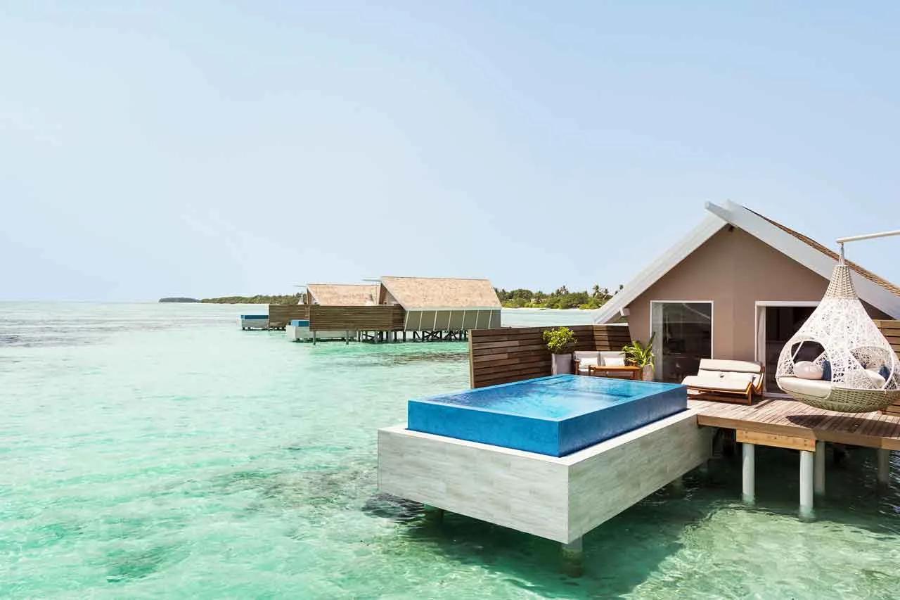 An Overwater Infinity Pool Villa's private pool extending toward the lagoon, with a hanging day bed on the deck
