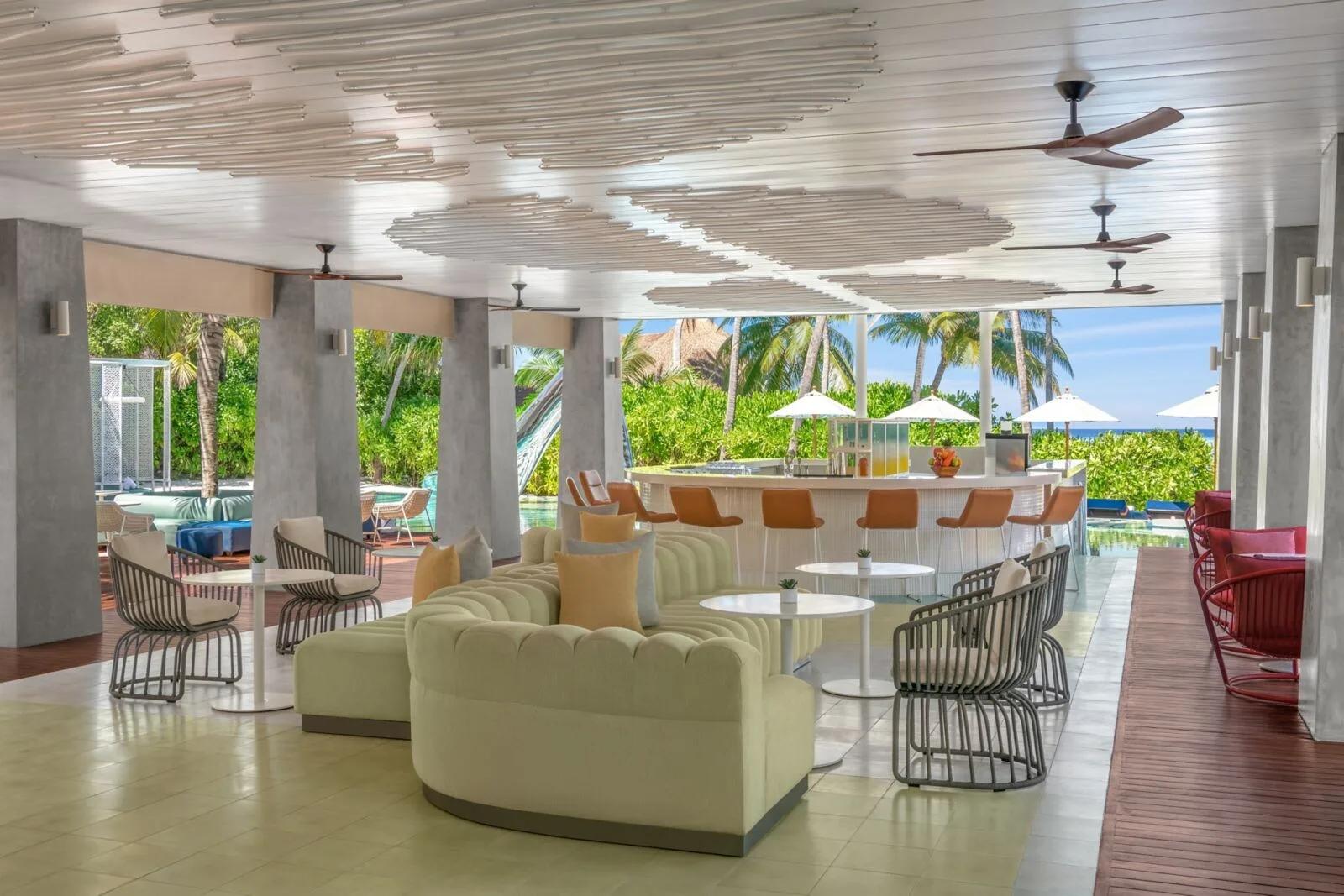 WET DECK, W Maldives' poolside lounge and bar, with seating under a shaded canopy overlooking the pool and gardens