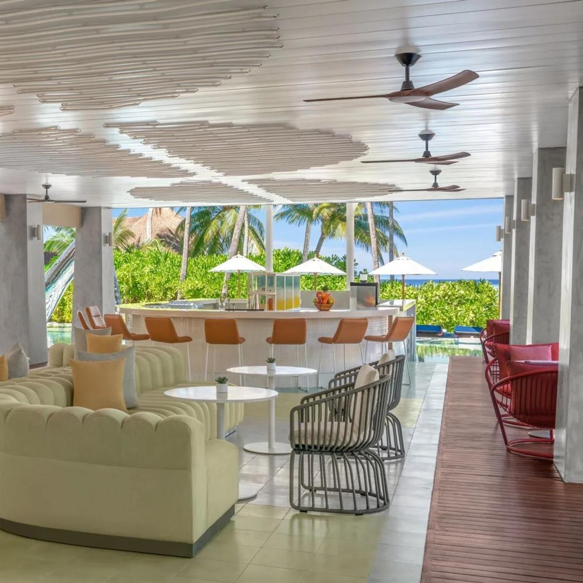 WET DECK, W Maldives' poolside lounge and bar, with seating under a shaded canopy overlooking the pool and gardens