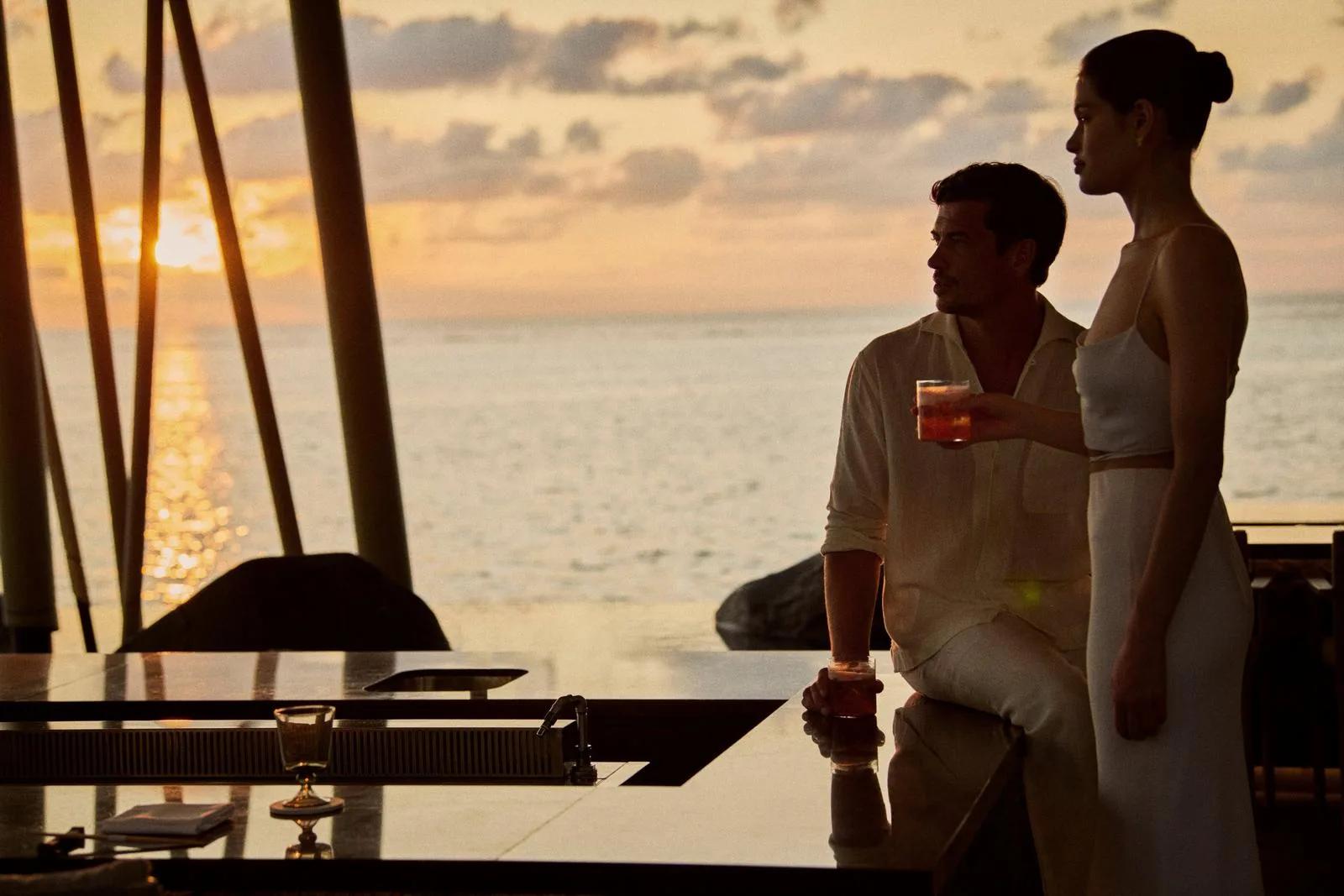 A couple at a bar counter at sunset, the ocean beyond — standing in for Fanditha, One&Only Reethi Rah's beachside restaurant, since no dedicated Fanditha photograph was collected