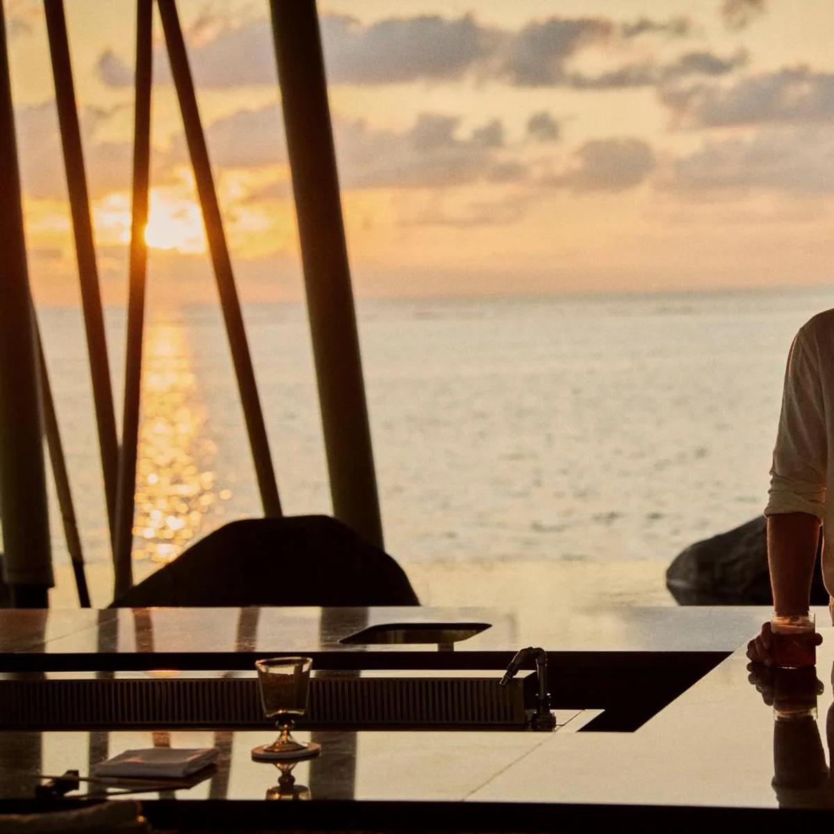 A couple at a bar counter at sunset, the ocean beyond — standing in for Fanditha, One&Only Reethi Rah's beachside restaurant, since no dedicated Fanditha photograph was collected