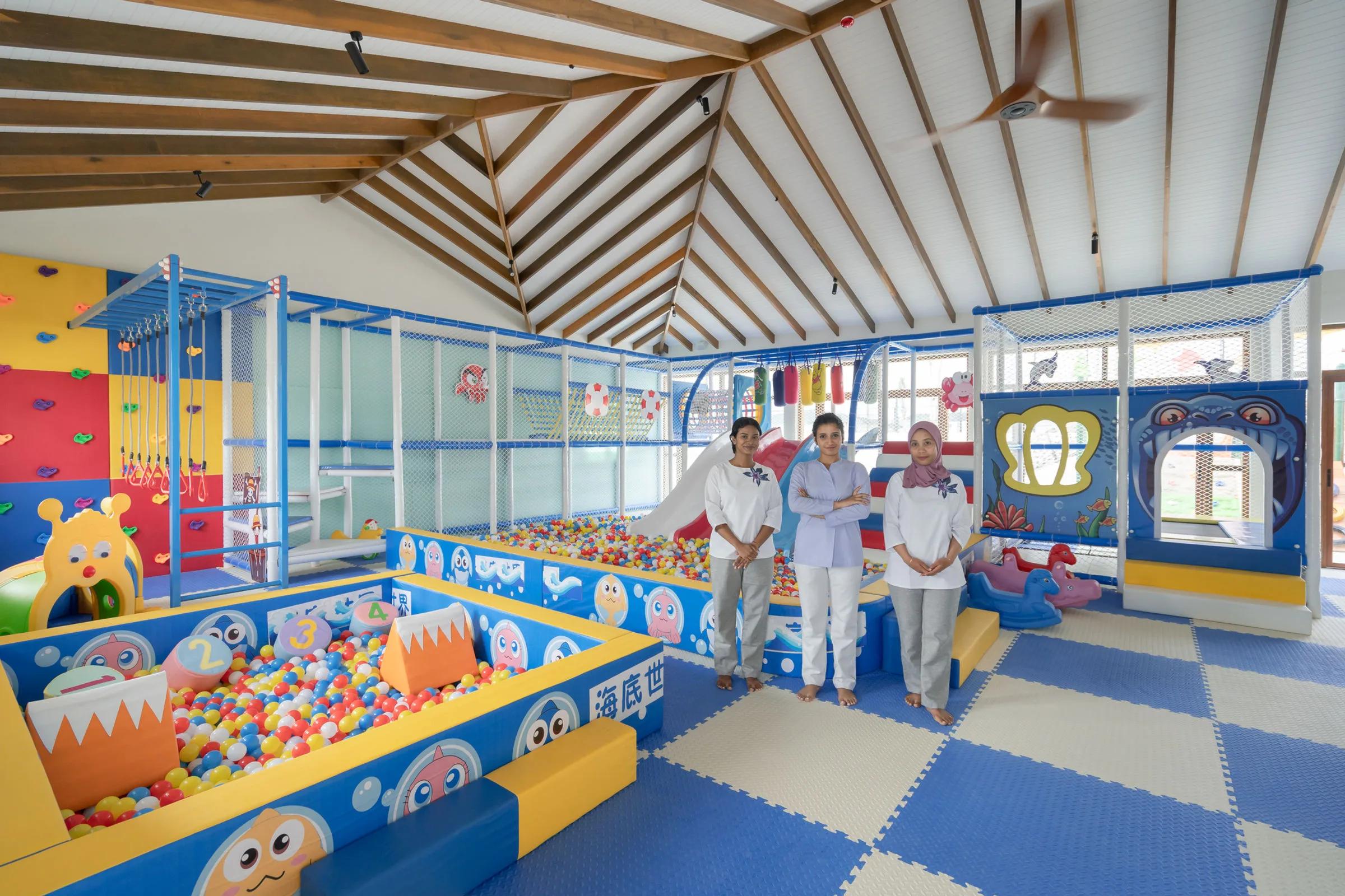 Kiddie Cove's colourful ball pit and climbing wall, staff members standing beside the play equipment