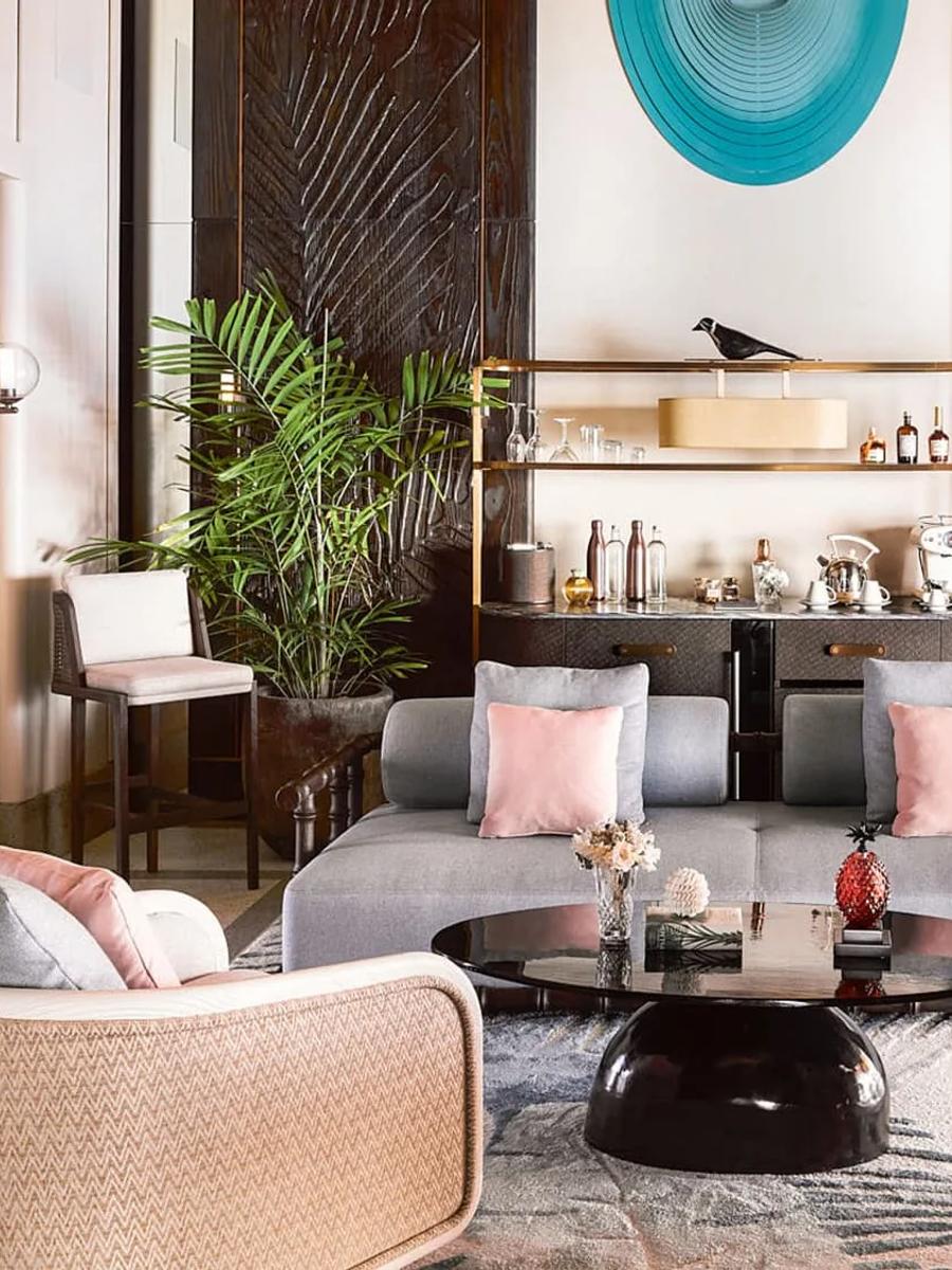 The living room of a Luxury Water Villa with Pool, with a bar cart, bookshelf and the lagoon visible through the doorway