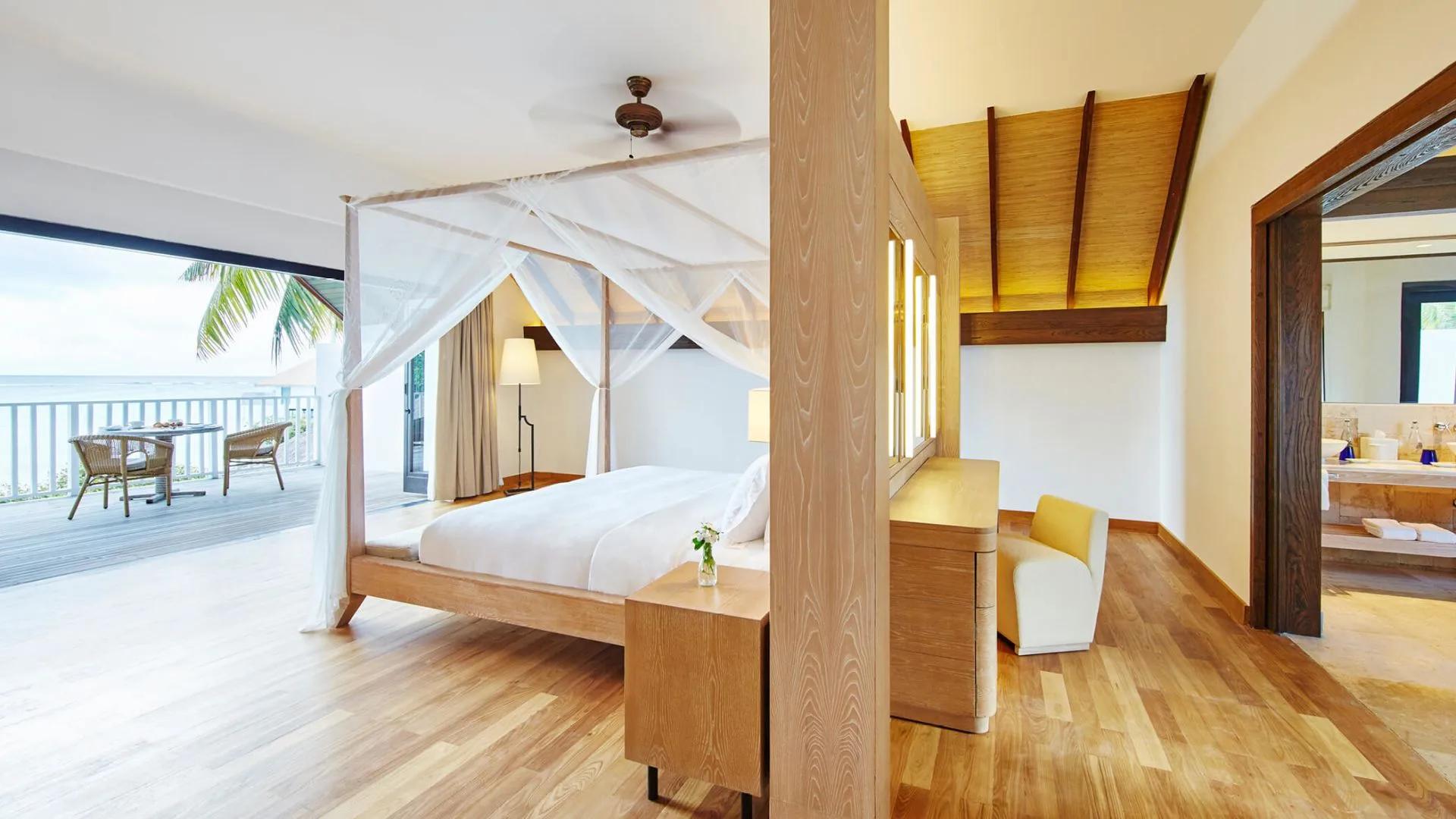 Canopy bed in an upstairs bedroom with balcony doors open to palm trees and the lagoon