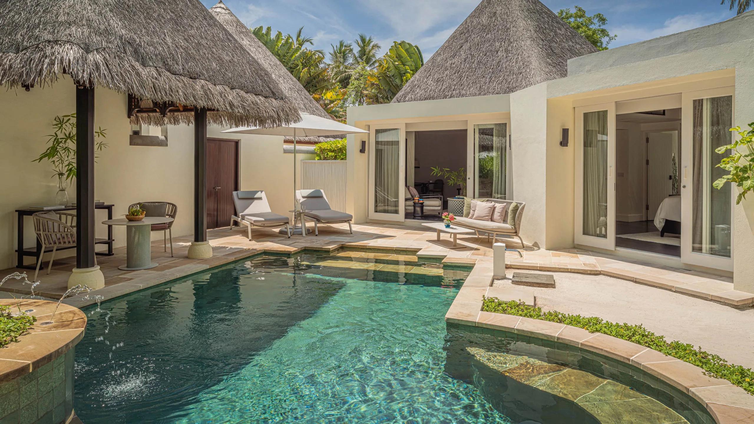 The Two-Bedroom Beach Pavilion's private pool and courtyard, framed by thatched roofs and palm trees