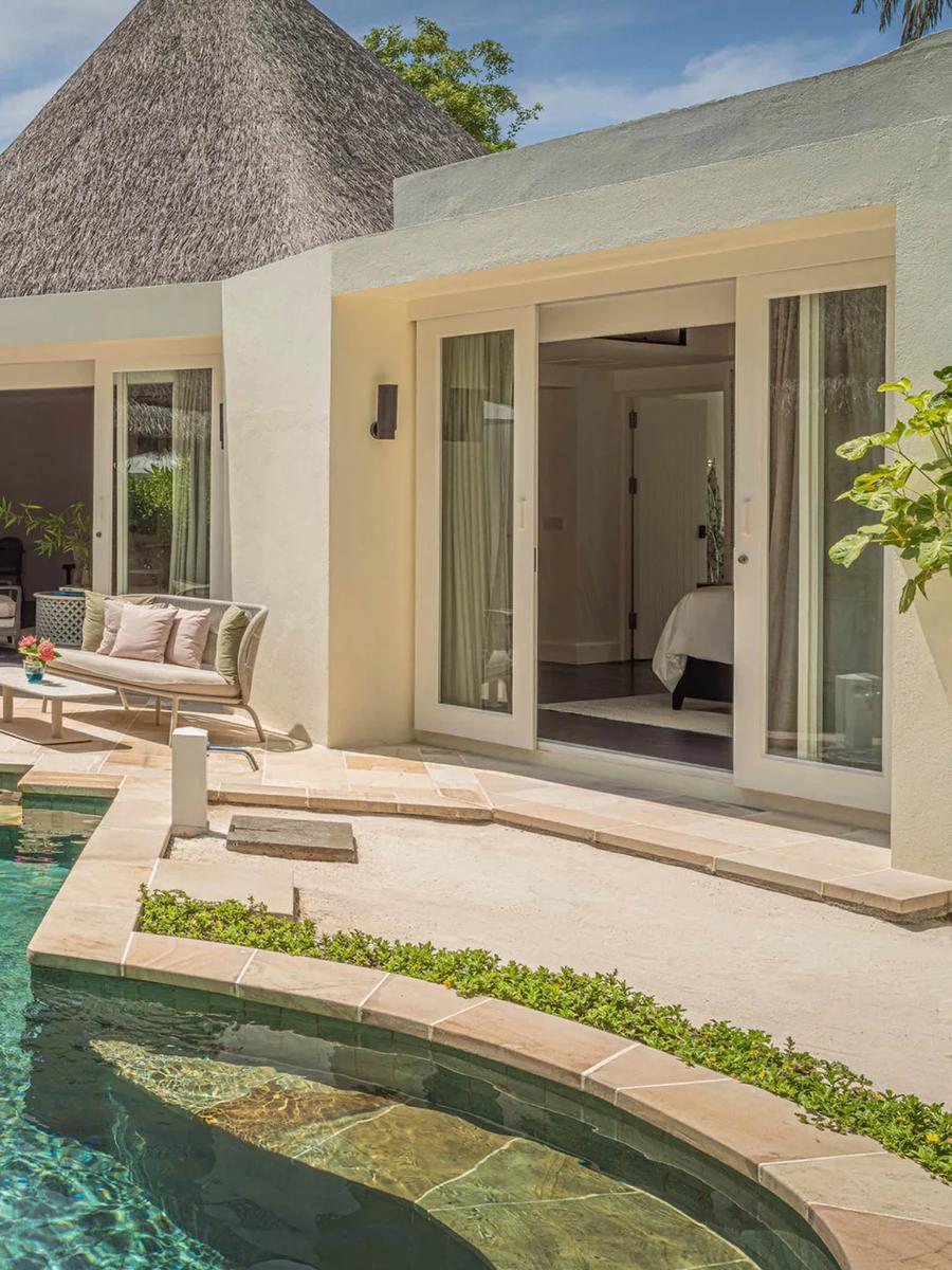 The Two-Bedroom Beach Pavilion's private pool and courtyard, framed by thatched roofs and palm trees