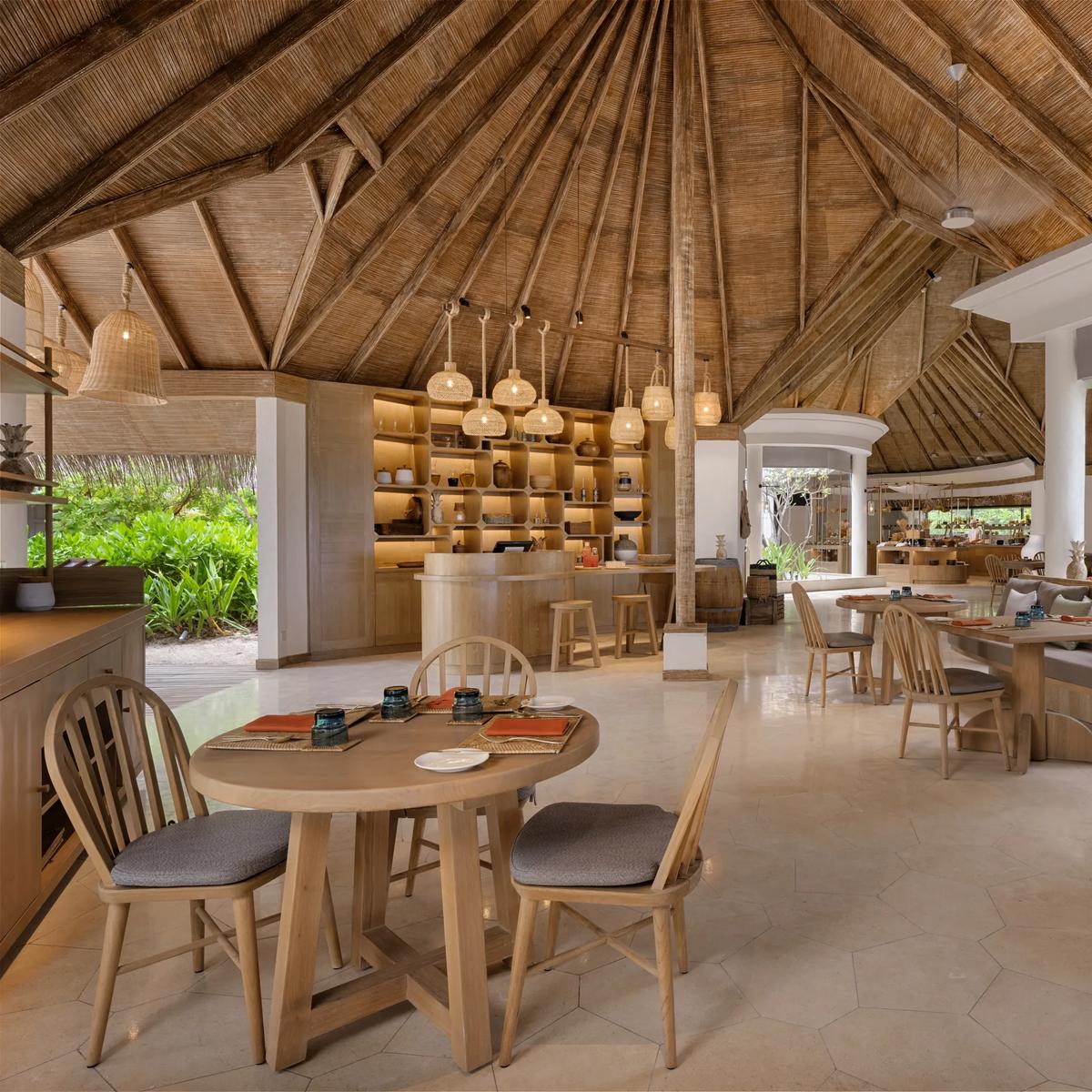 The bright, high-ceilinged interior of The Market restaurant, with dining tables, banquette seating, and an open kitchen counter.