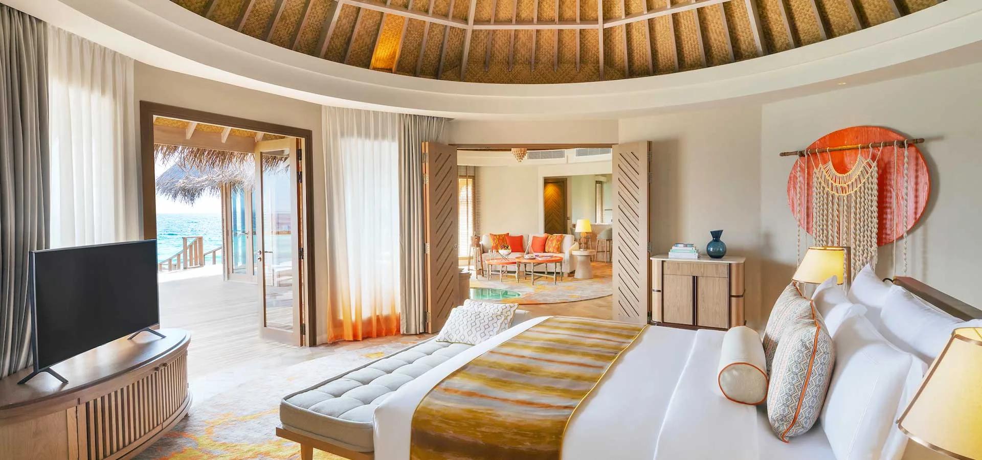 An Ocean Residence living and dining room, doors open to a pool deck with palm trees and the ocean.