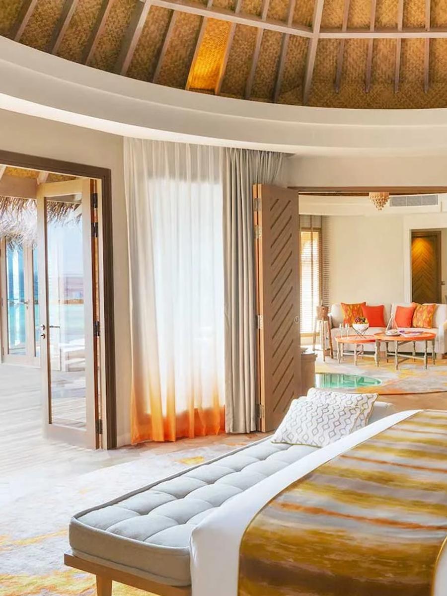 An Ocean Residence living and dining room, doors open to a pool deck with palm trees and the ocean.