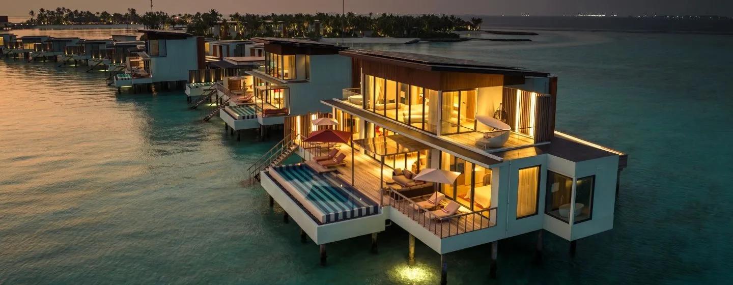 A two-storey overwater villa at SO/ Maldives at twilight, its rooftop deck and freestanding tub visible above a private pool — matching the Two-Bedroom Ocean Water Pool Atelier's two-level design