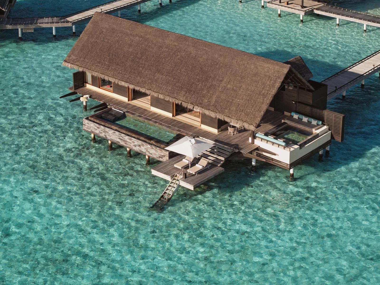 Aerial view of a Grand Water Villa at One&Only Reethi Rah, a glass-edged pool suspended over the reef