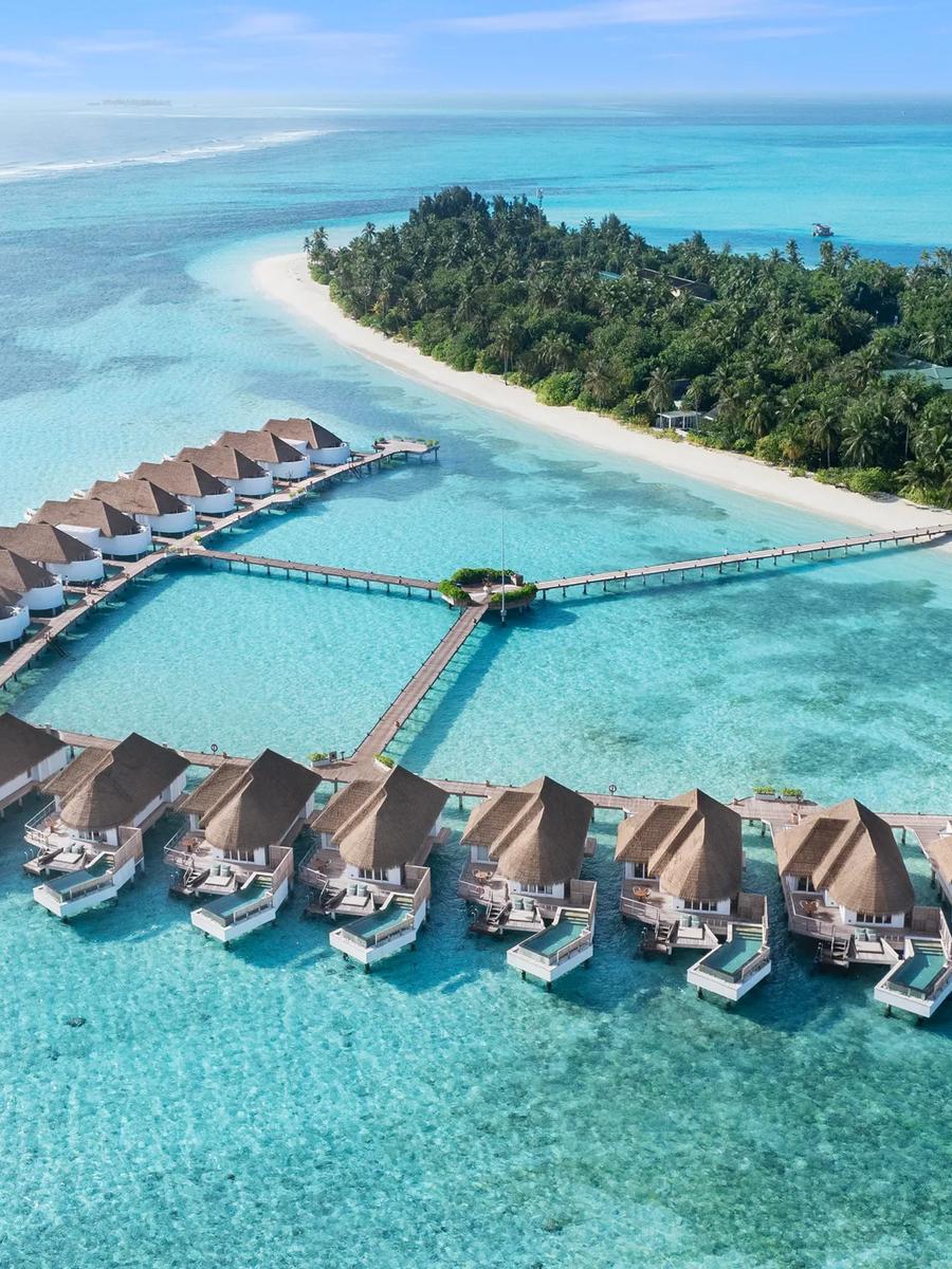 Aerial view of Six Senses Kanuhura's overwater villas arranged in a V-shaped jetty over the turquoise lagoon.