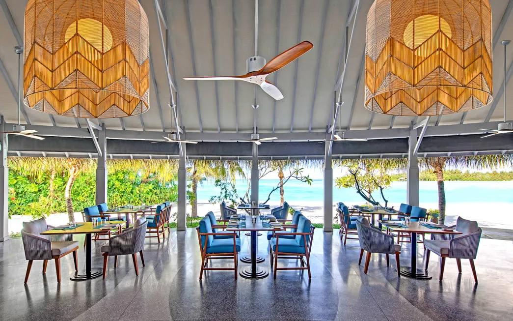Fushi Café's open-air dining room with rattan lampshades and beach views