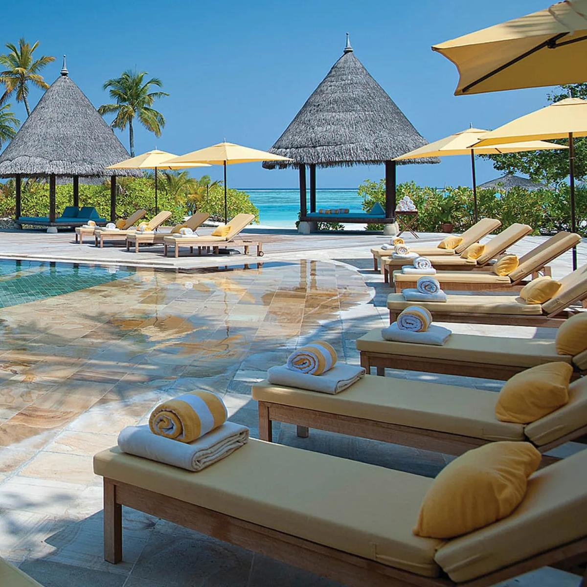 The main infinity pool with loungers and thatched cabanas facing the lagoon