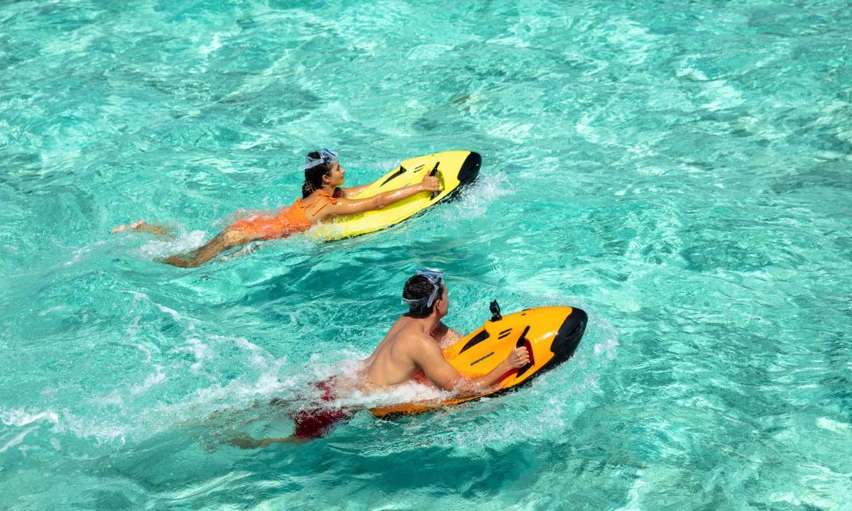 Two guests riding sea-bob underwater scooters through Kandima's clear lagoon